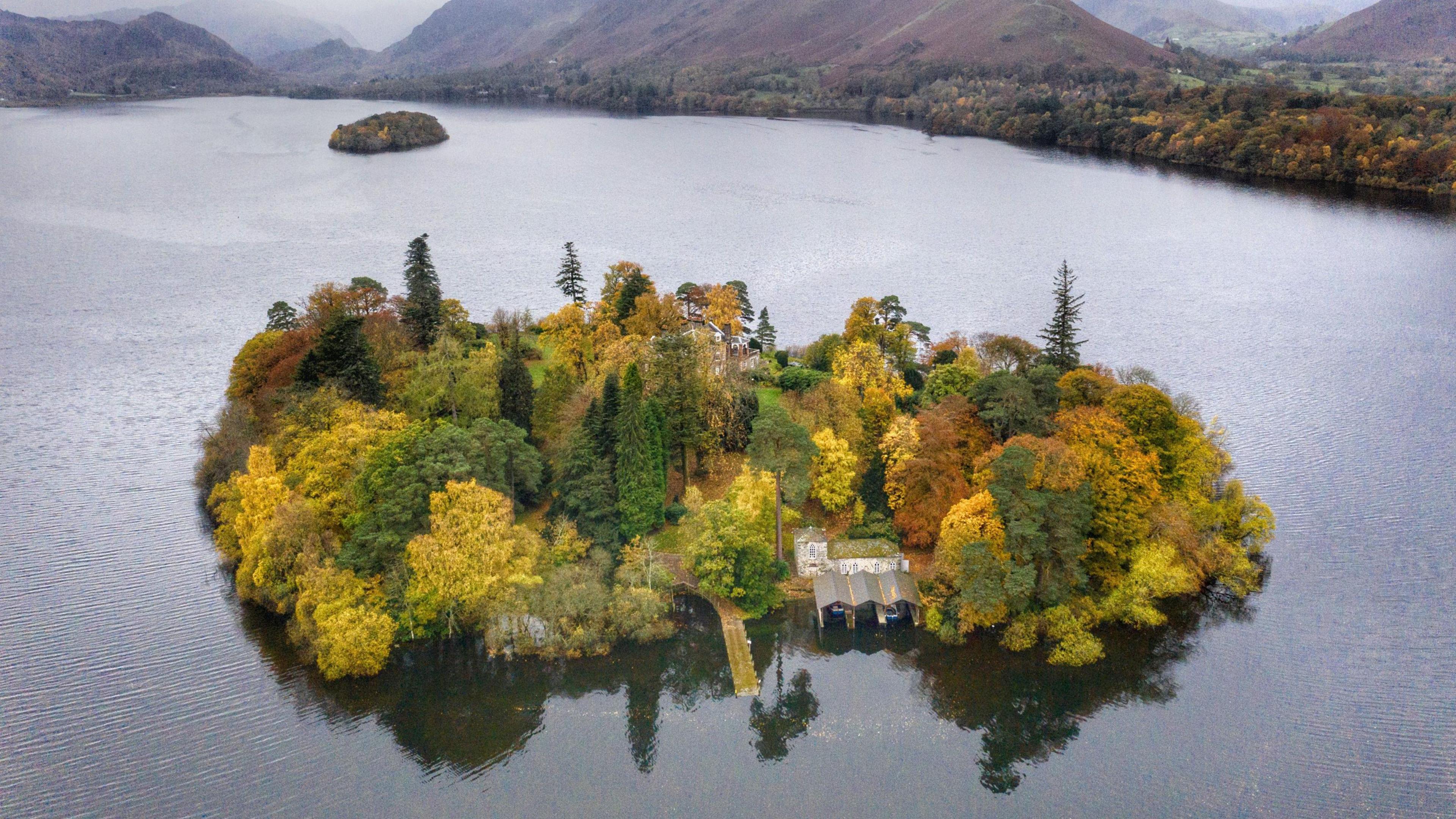 An aerial view of Derwent Island. The island is covered in trees, with a property and a boathouse visible on the edge of one of the shores.