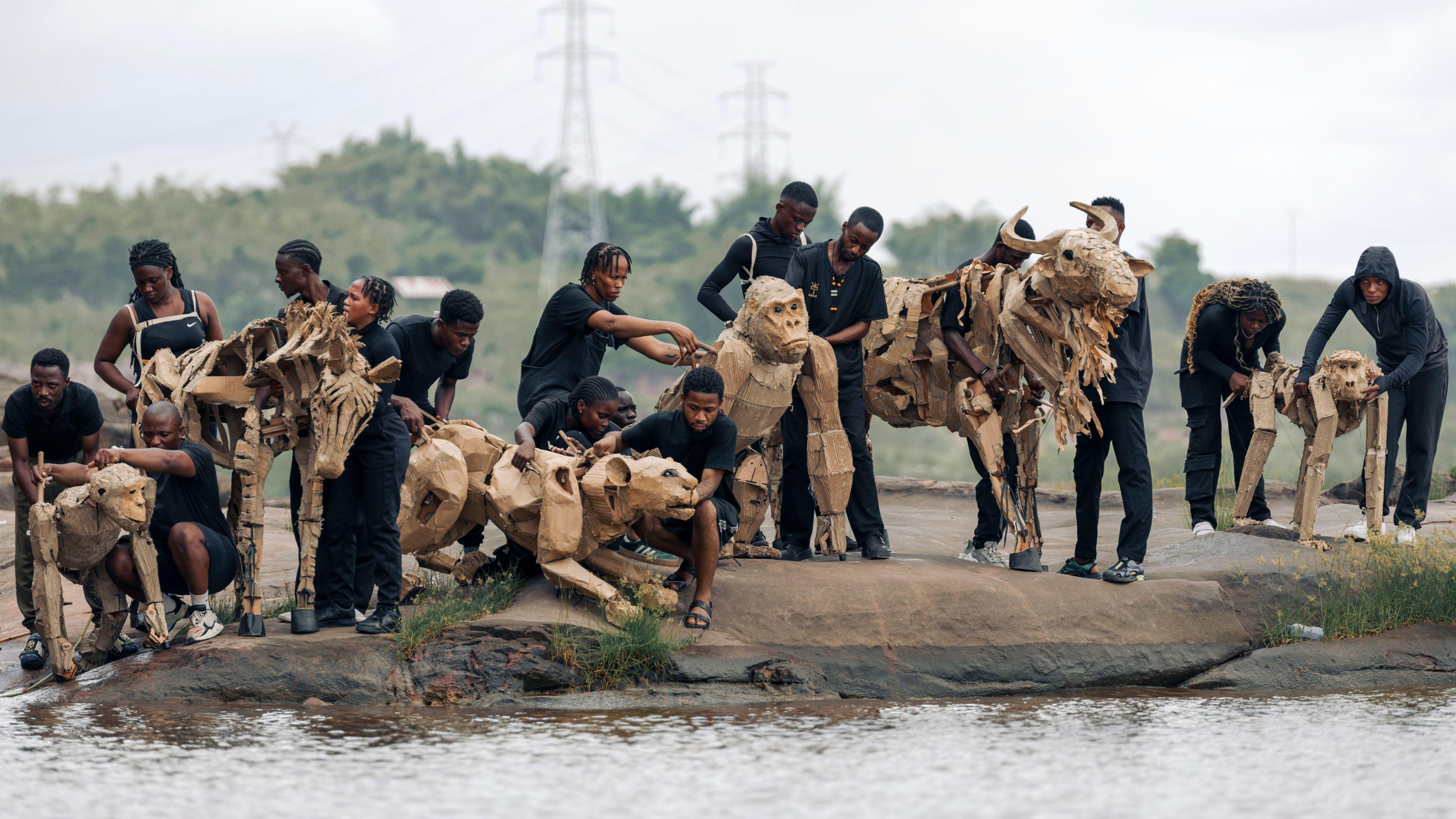 Sixteen people wearing black clothes stood alongside six life-sized puppet animals along the Congo Basin. 