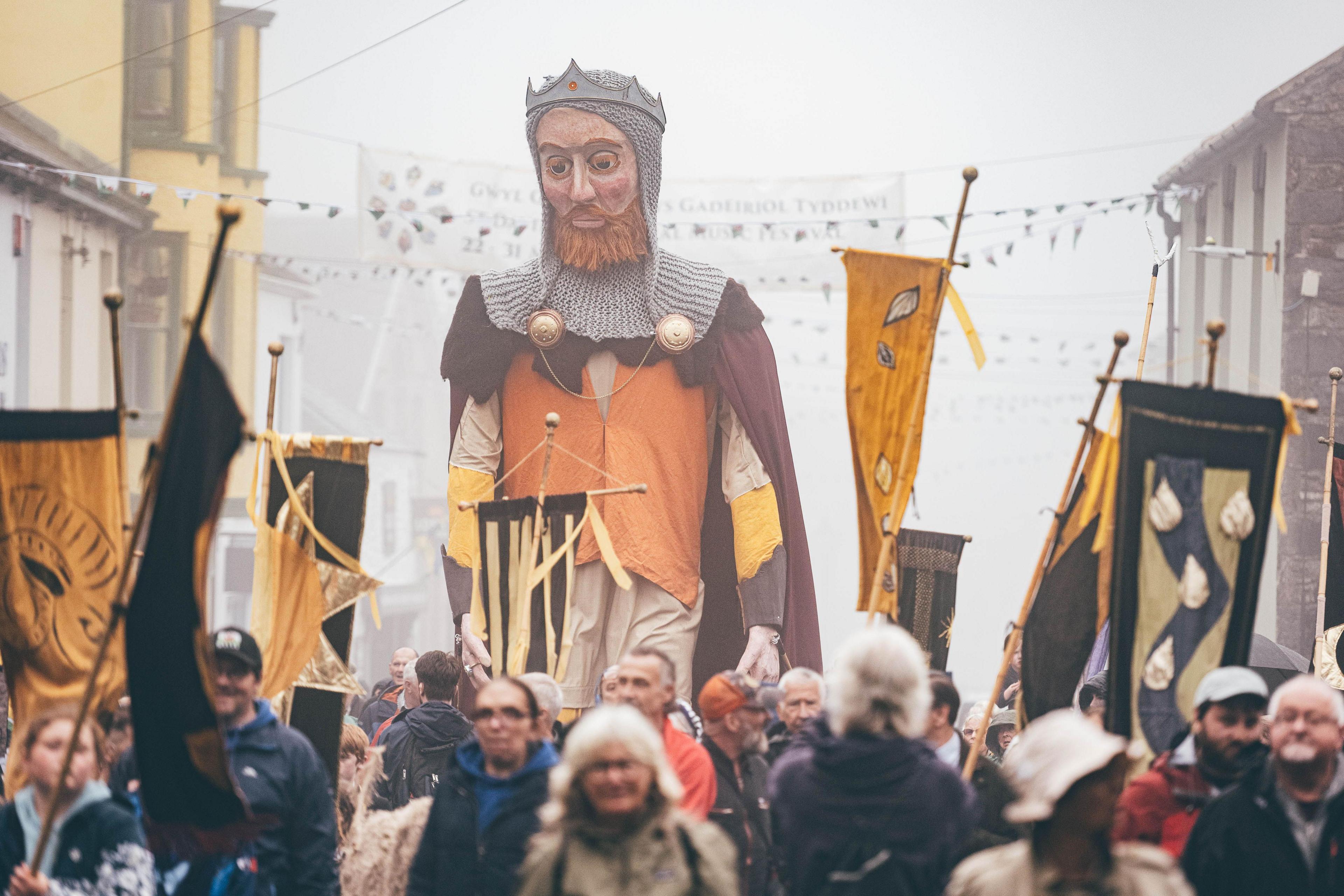 Gorymdeithio trwy ddinas lleiaf Cymru, Tyddewi, a baneri lliwiau Dewi Sant yn cyhwfan