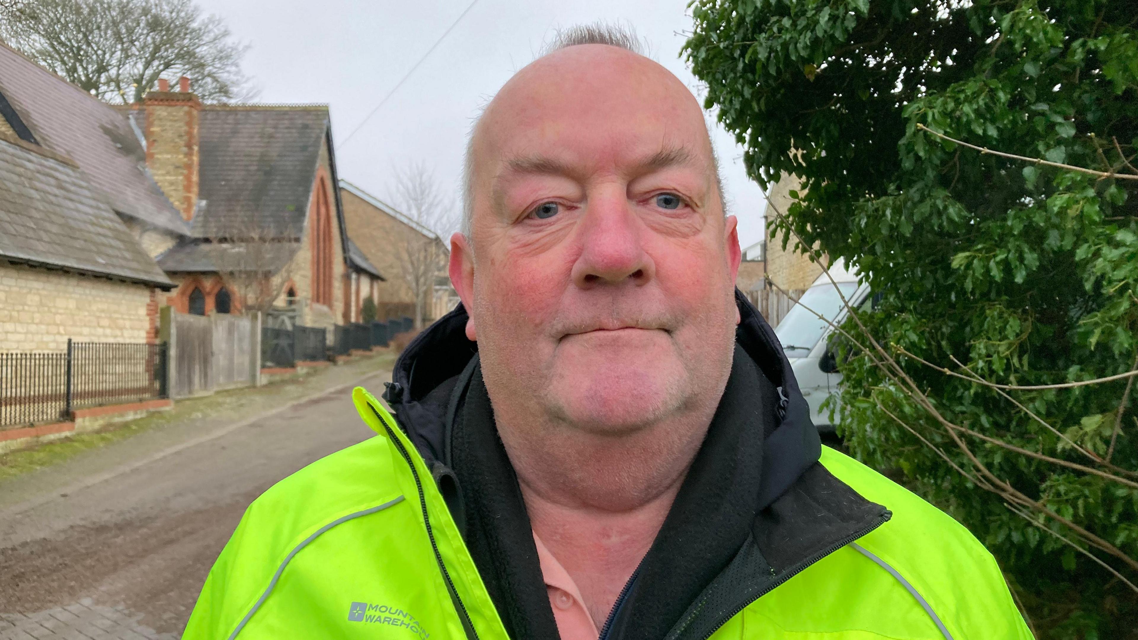 A head and shoulders photo of Rob, one of the speedwatchers. He is mostly bald, and wearing a high-vis jacket over a black hoodie. 