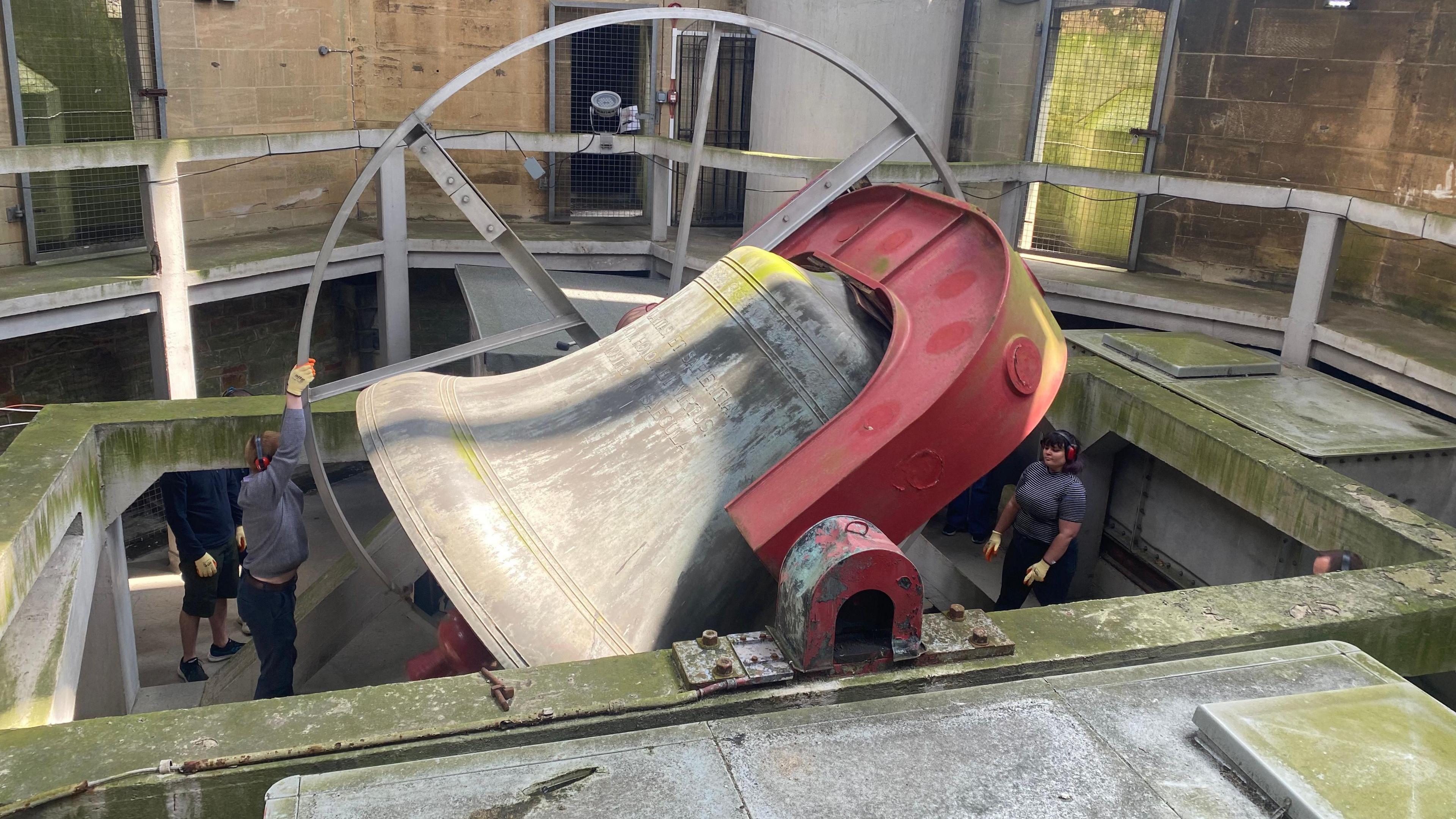 Two bell ringers spin a giant metal wheel that rings the large cast iron bell known as Great George in the Wills Memorial Building