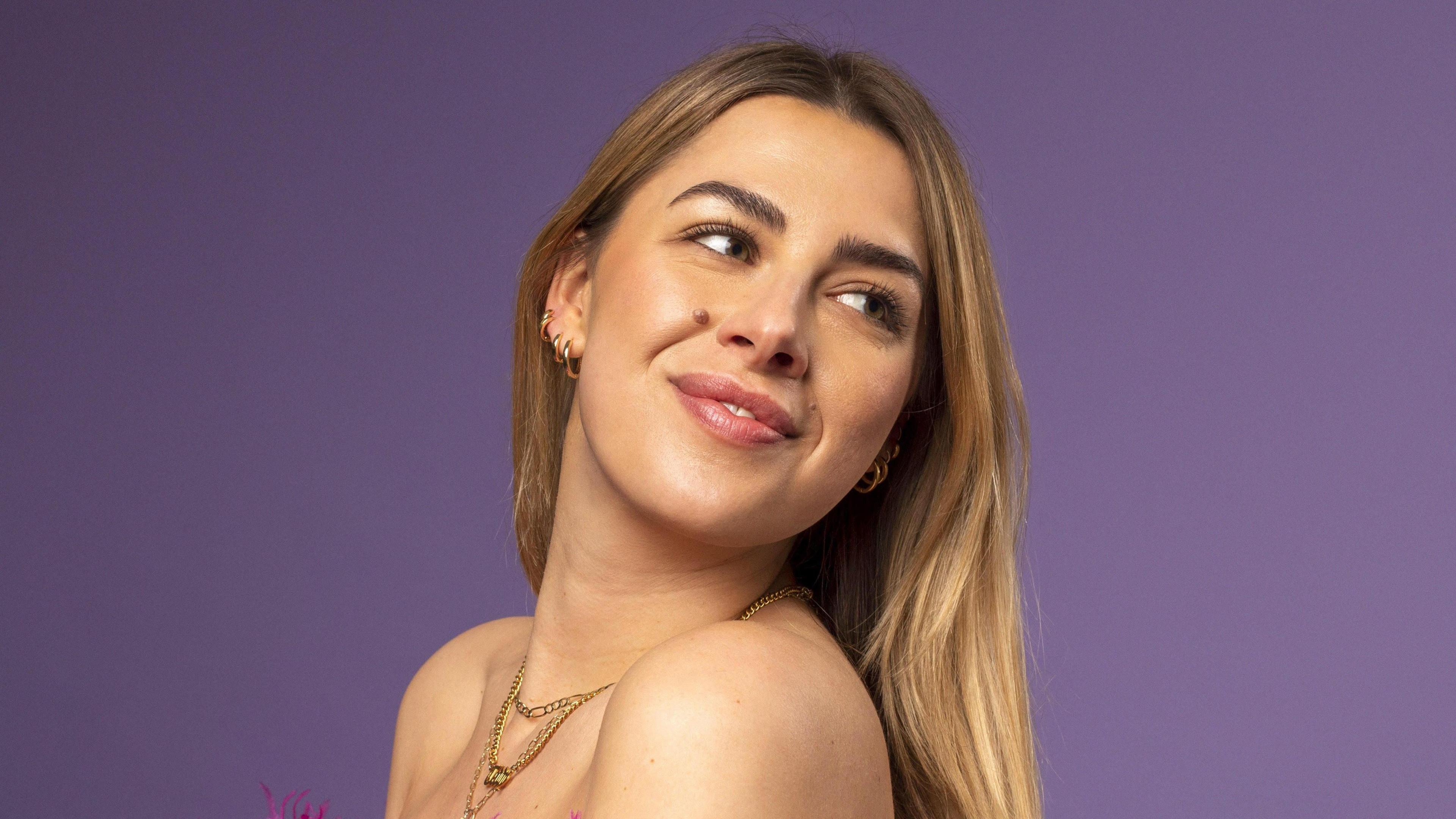 A young women with blonde hair, wearing gold jewellery. 
