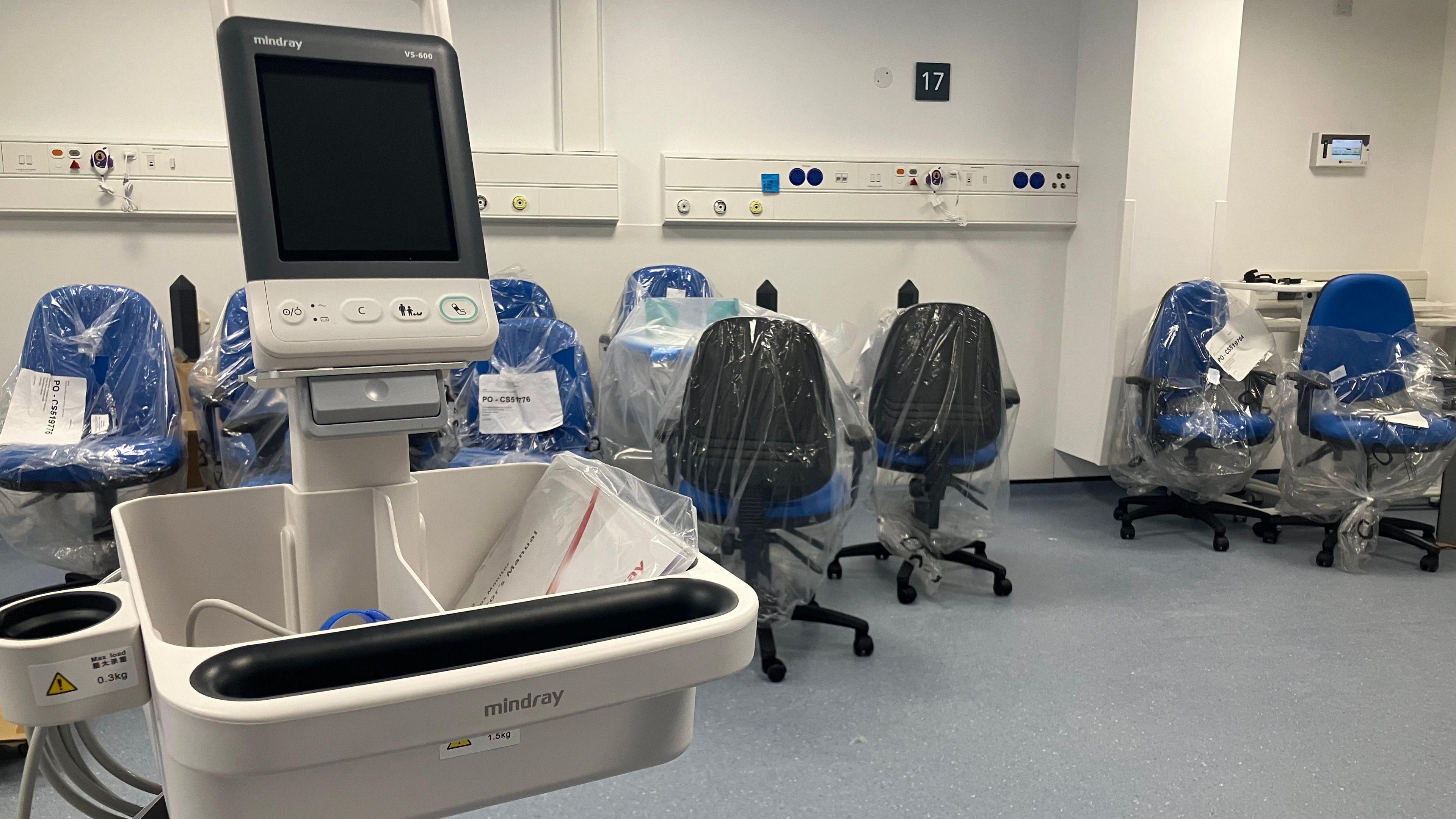 The East Midlands NHS Planned Care Centre, at Leicester General Hospital, is nearing completion. A piece of medical equipment is in the foreground with unused chairs, still wrapped in plastic, dotted around a room.