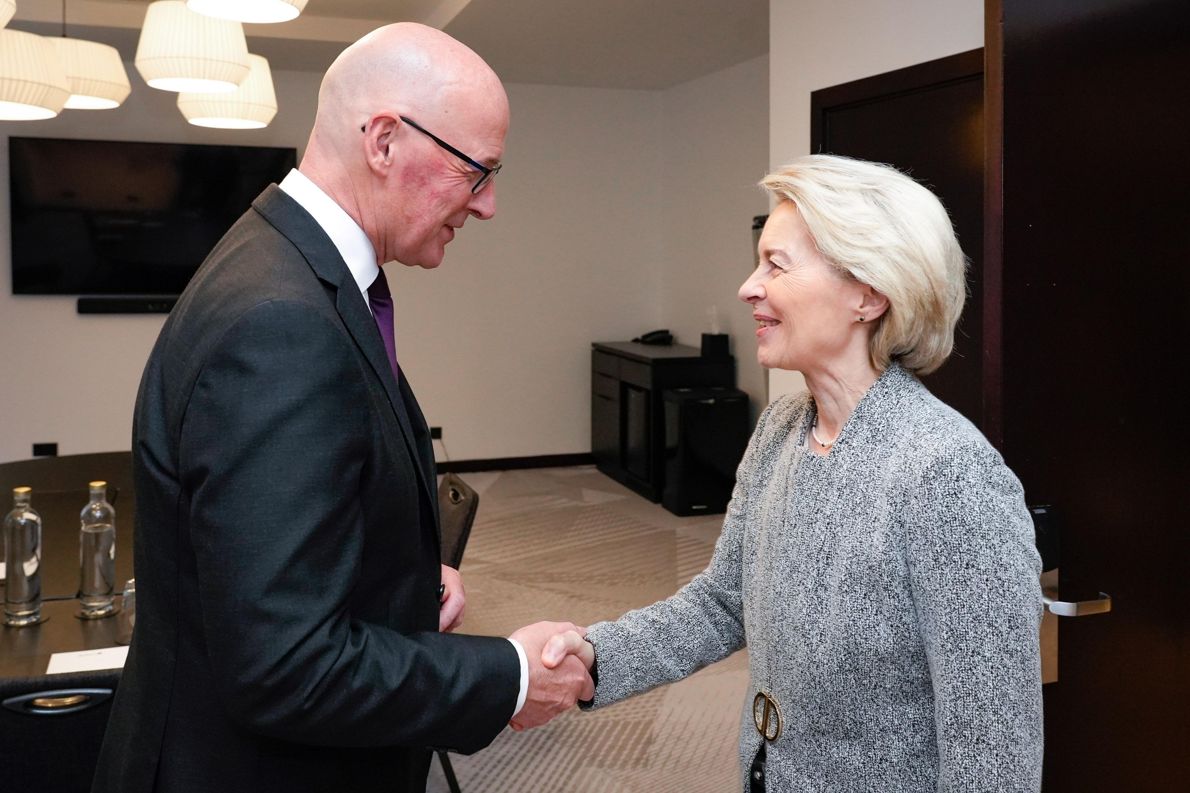John Swinney, who has a bald head and is wearing a black suit jacket, shakes the hand of Ursula von der Leyen, who has short blonde hair and has grey suit jacket with a gold fastening.