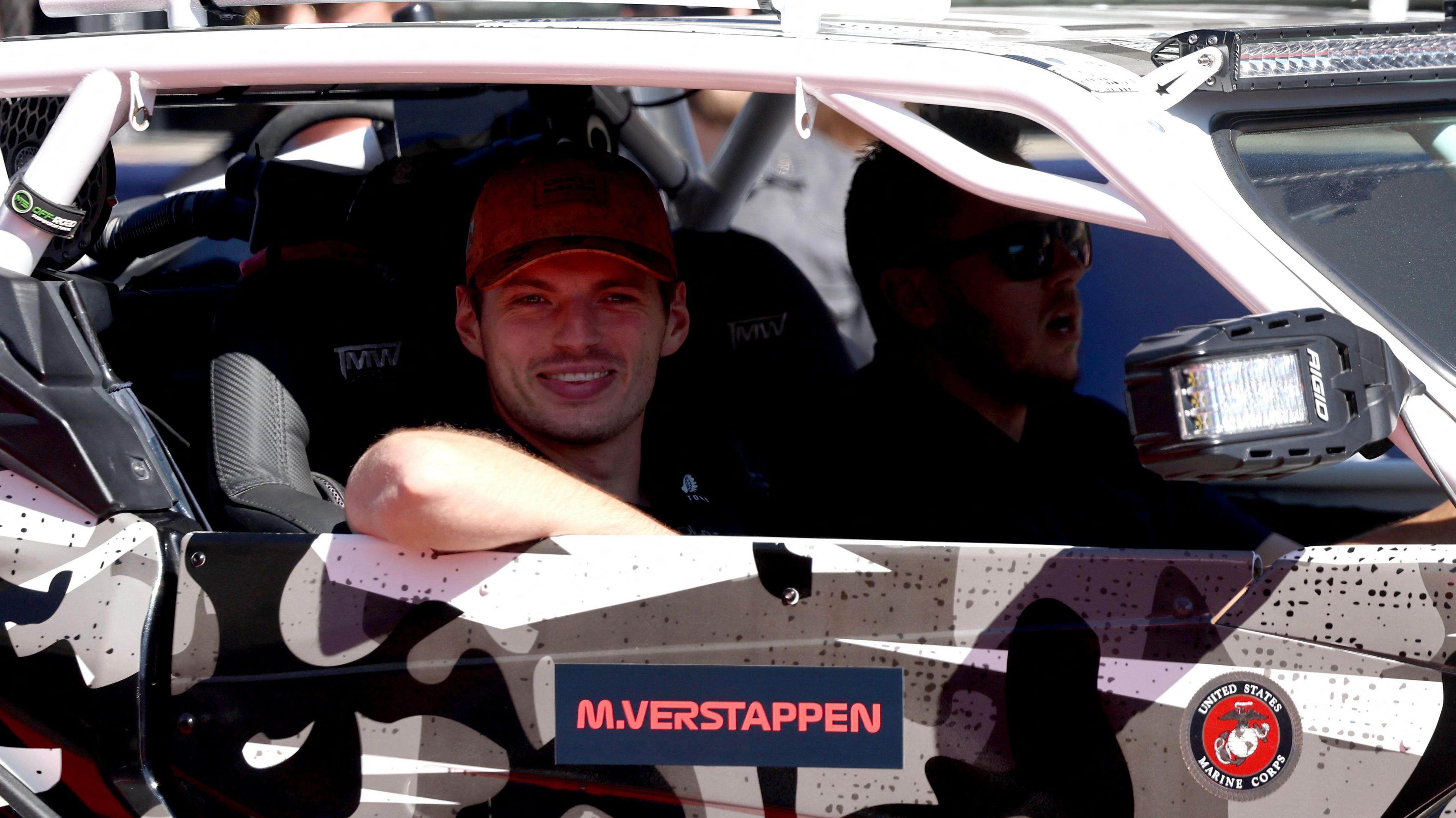 Max Verstappen seated in a camouflage-patterned off-road vehicle during the drivers’ parade