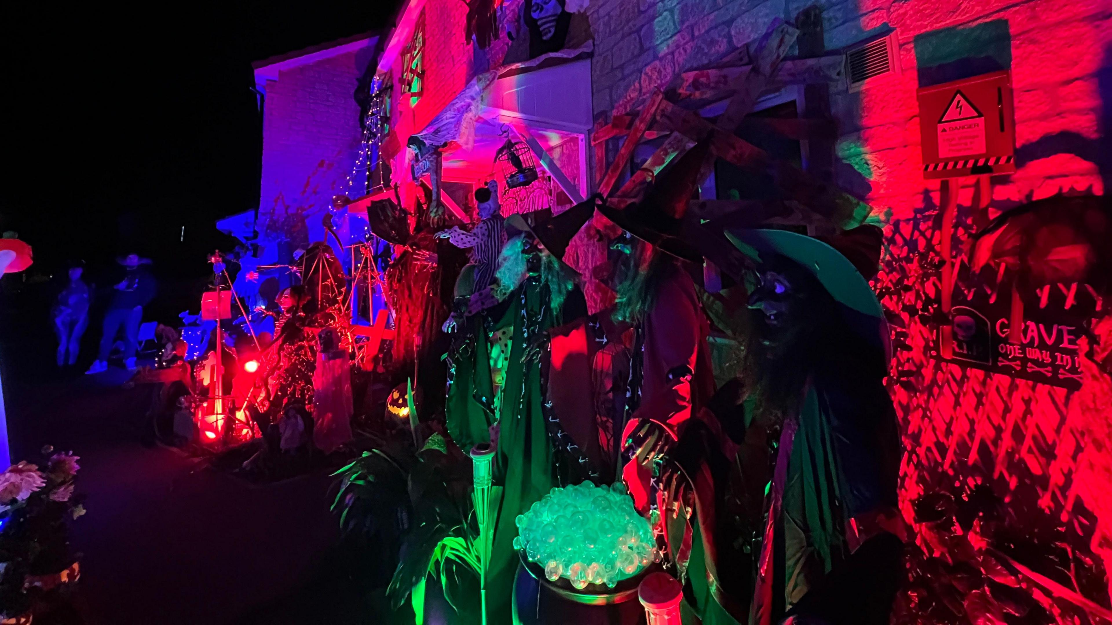 A haunted house showing red light, bright lights and a witch with a bubbling cauldron