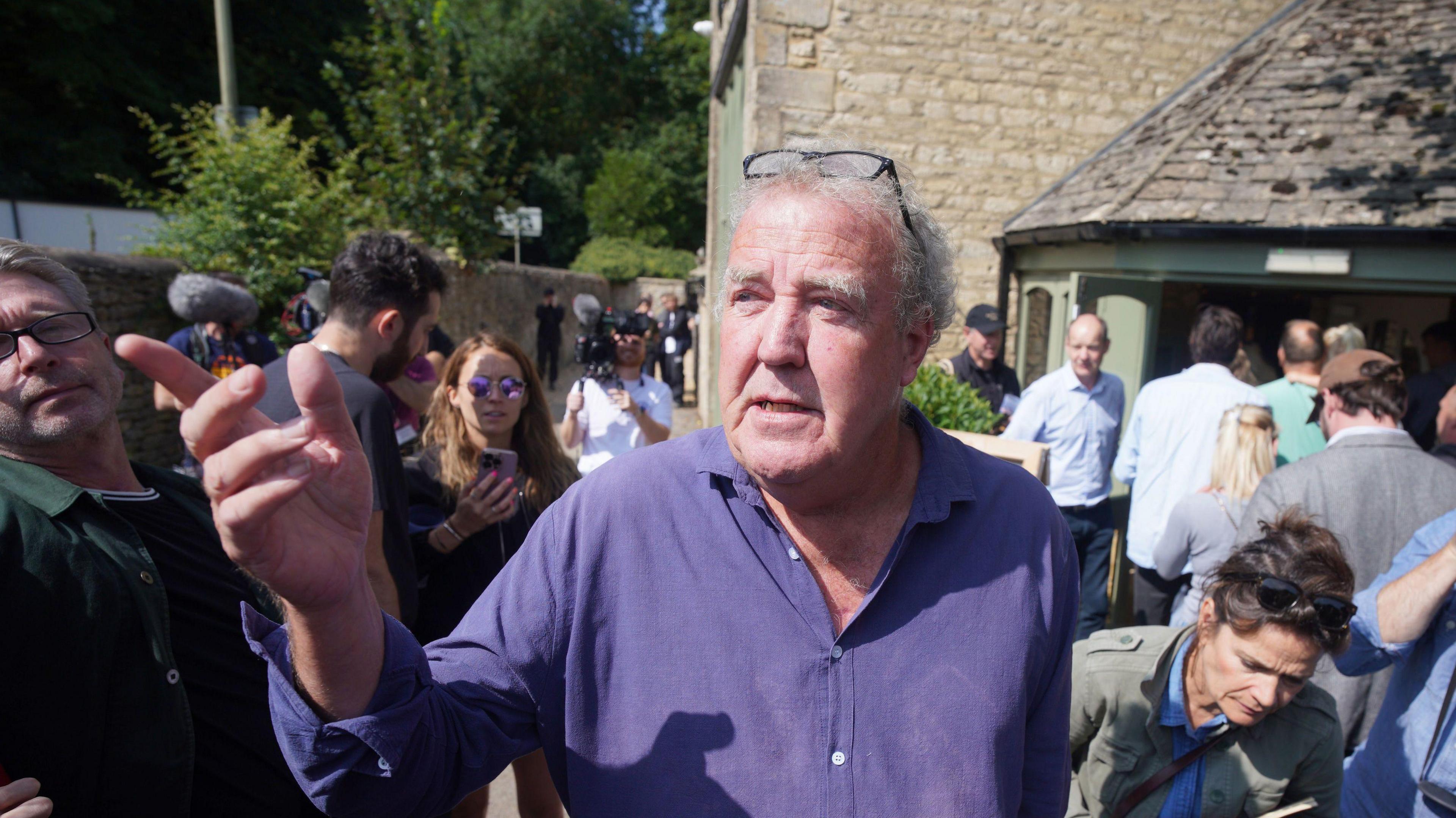 Jeremy Clarkson stands outside his new pub surrounded by crowds. 