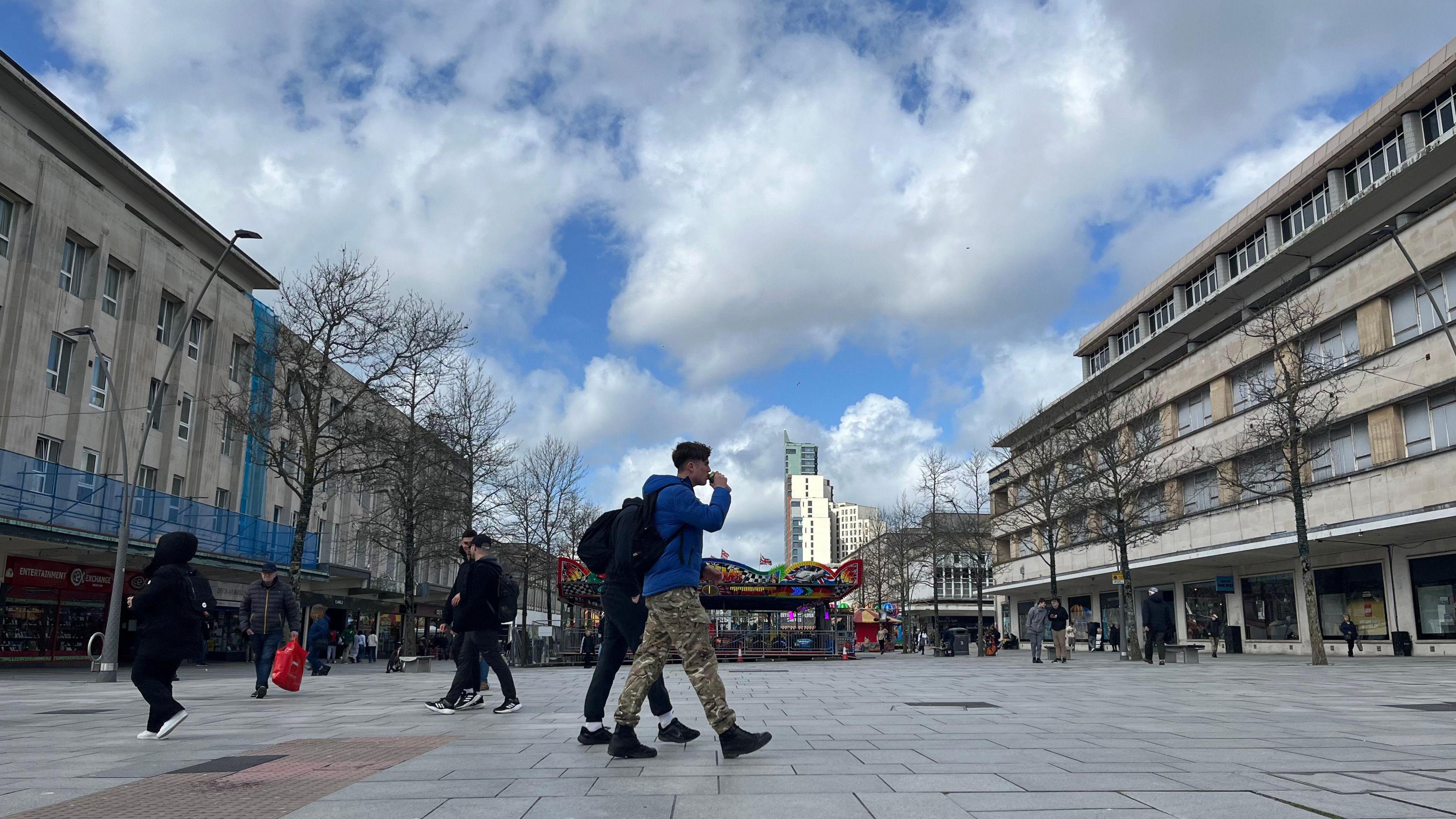 A view of Plymouth City Centre with shoppers walking around a pedestrianised area