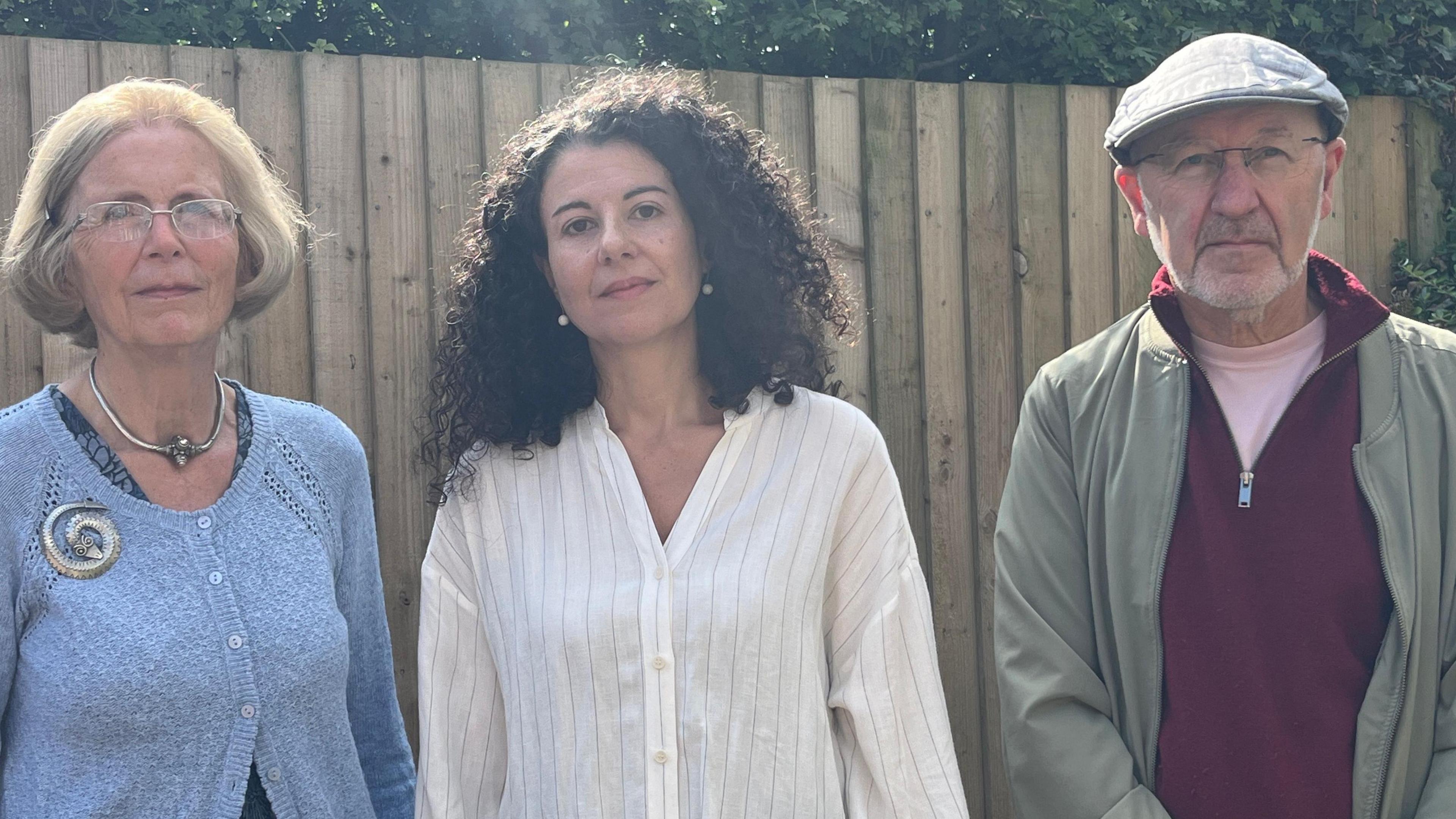 Left to right: Rosie Budd, Dr Stella Bolaki and Professor Stephen Banfield. Rosie is wearing a blue knit cardigan and has a short bob haircut. Dr Bolaki has long, dark curly hair and is wearing a white shirt, while Professor Banfield is wearing a maroon jumper, khaki jacket and flat cap. He is also wearing glasses.