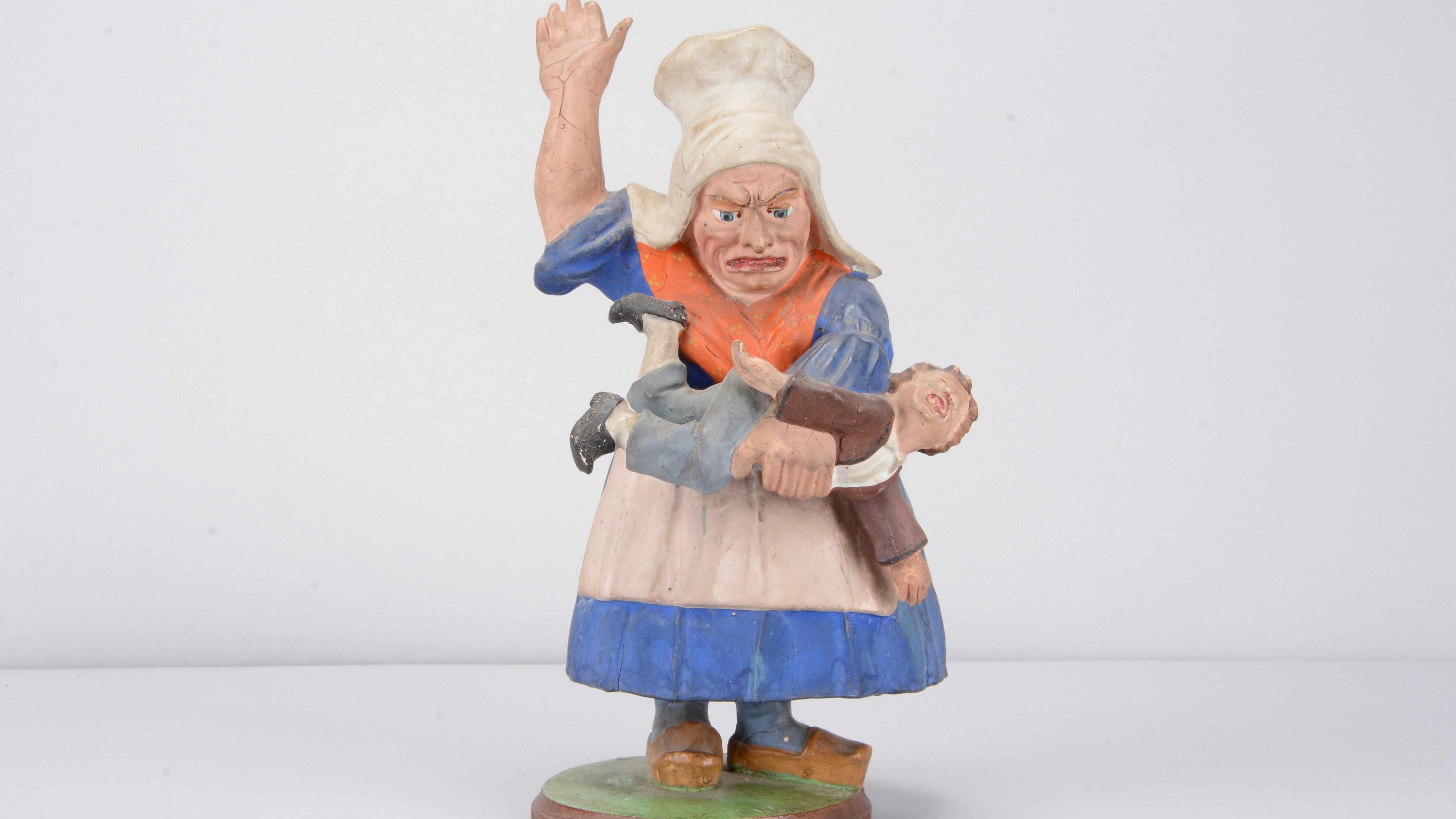 A Sonneberg composition nodder grotesque woman beating a child mid to late 19th Century toy.