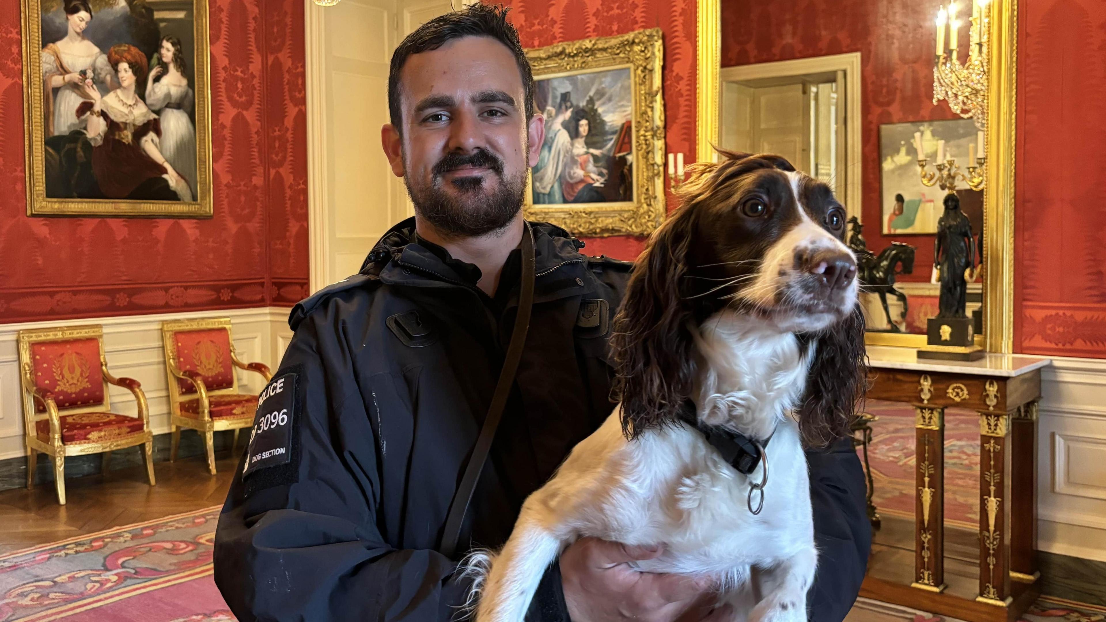 Sgt Ben Smith holding Hope in an ornately decorated red room with gold accents