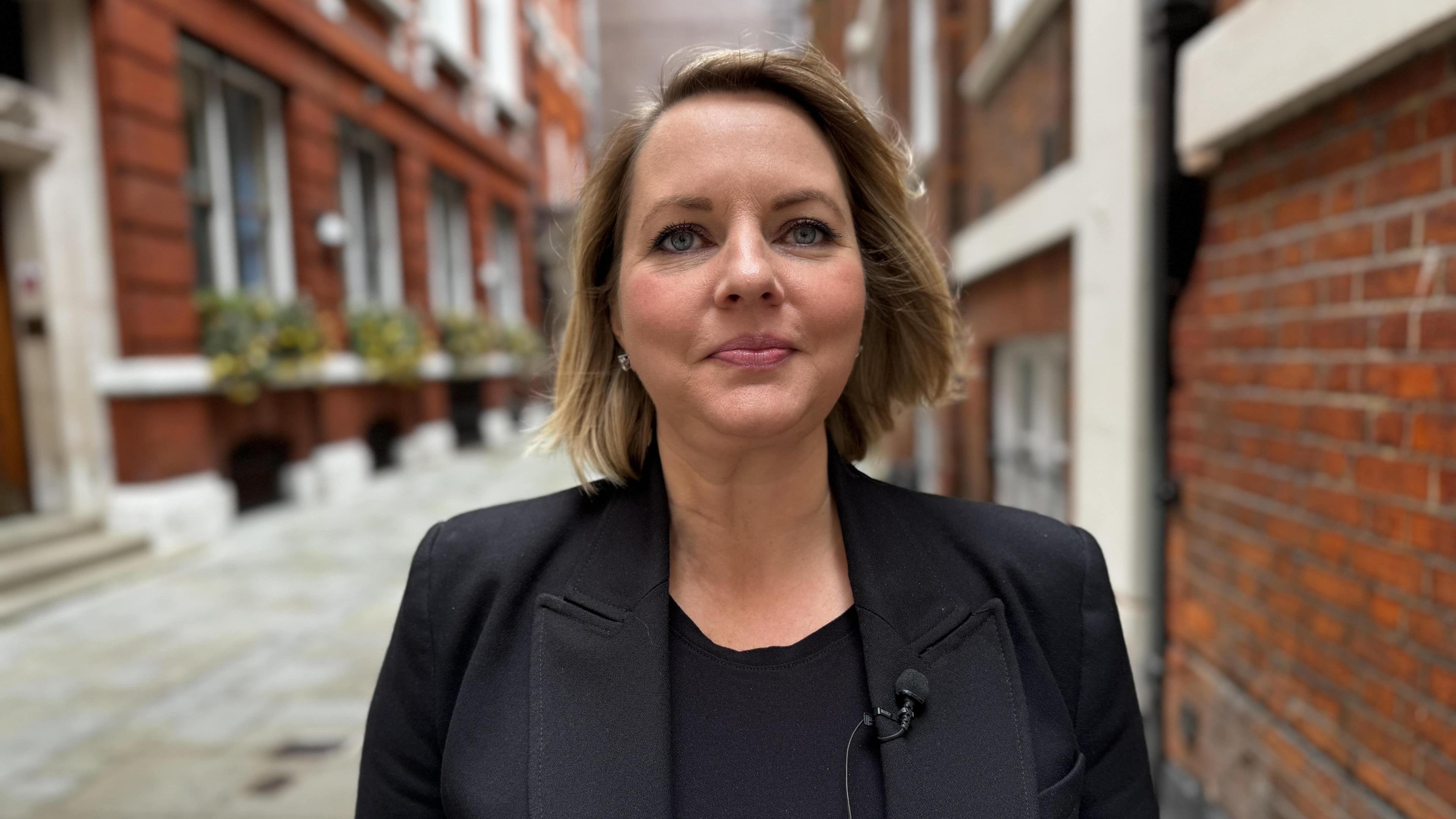 Kathleen Hallisey standing in a pedestrianised street, lined with red-brick buildings