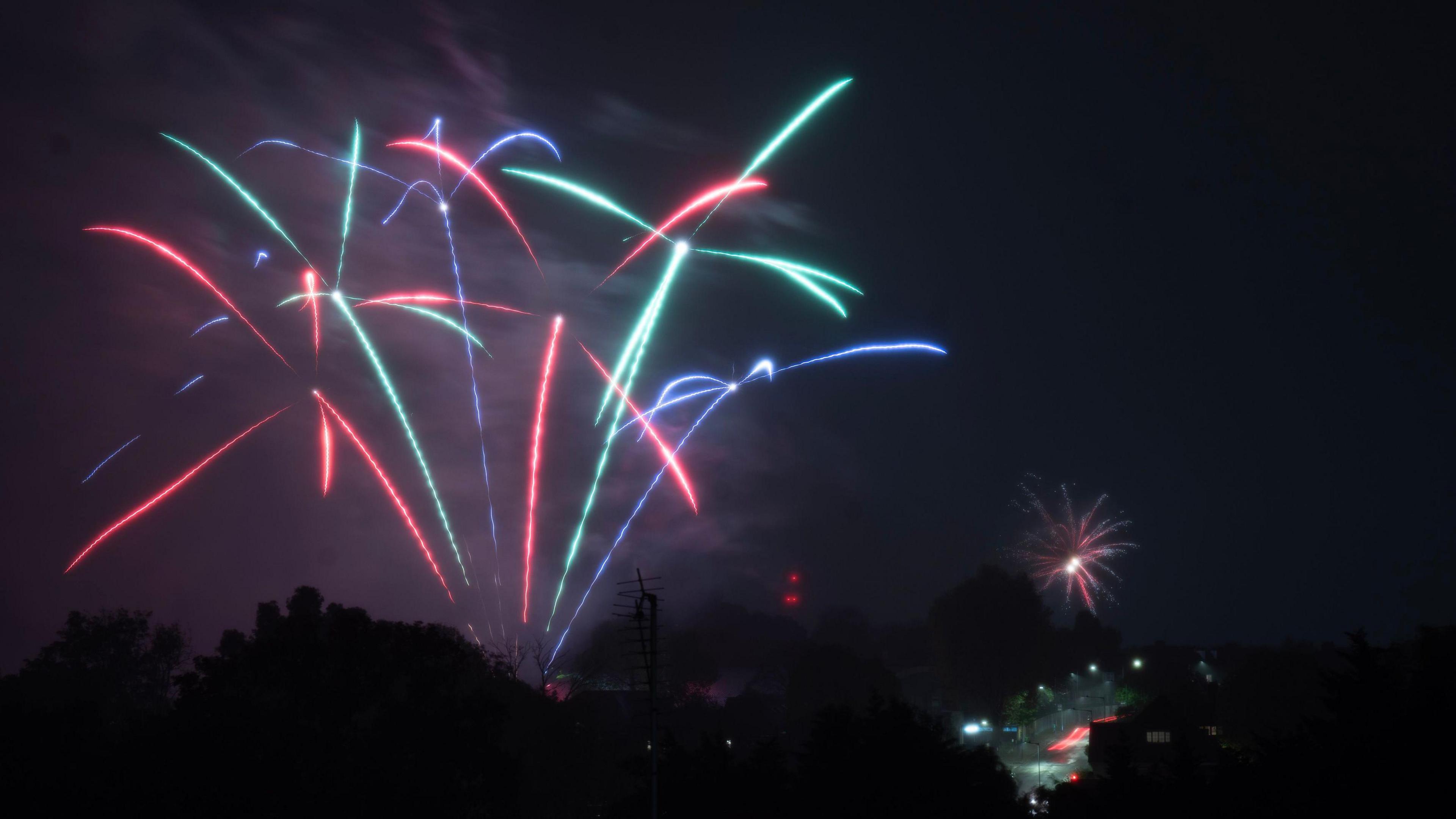 Fireworks in red, blue and green streaks across night sky 