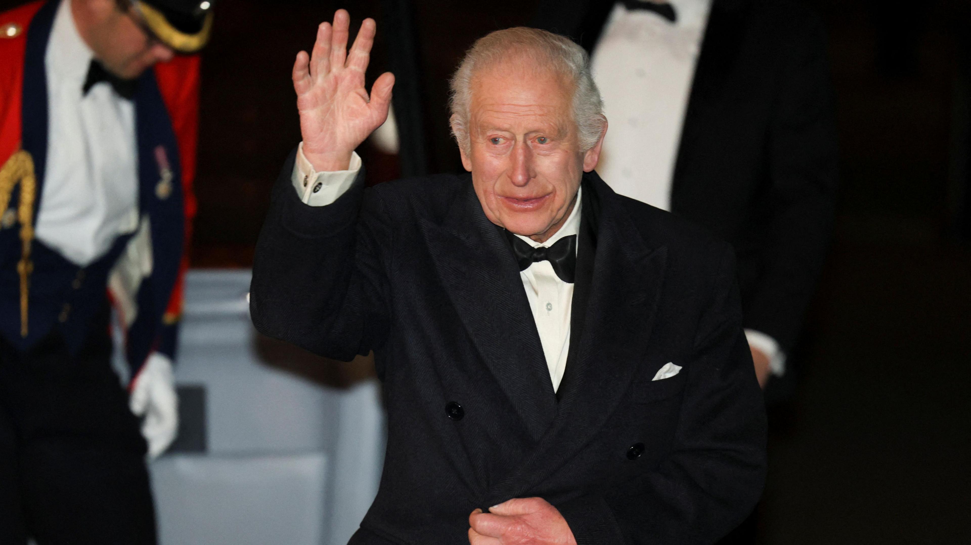 King Charles lifts a hand to wave as he walks from his car into the Royal Albert Hall