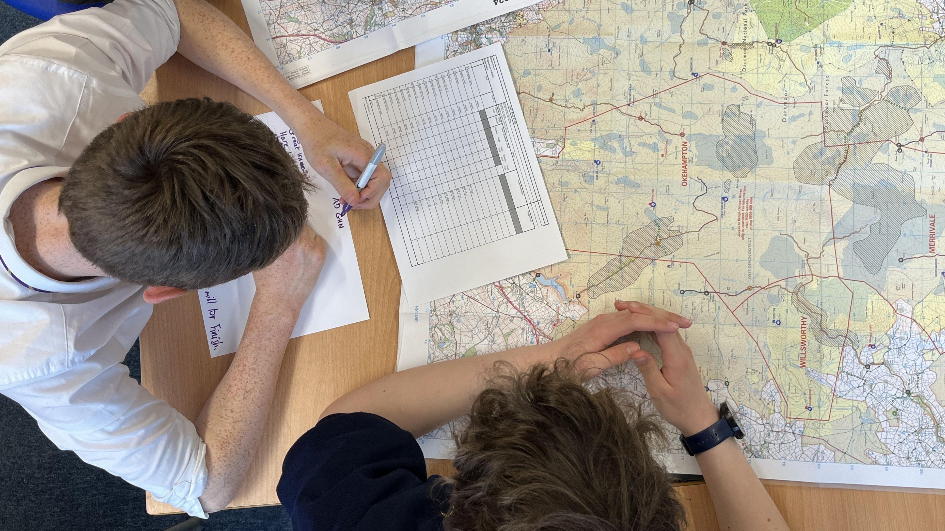 Photo from above looking down on two students with an OS map, planning their route