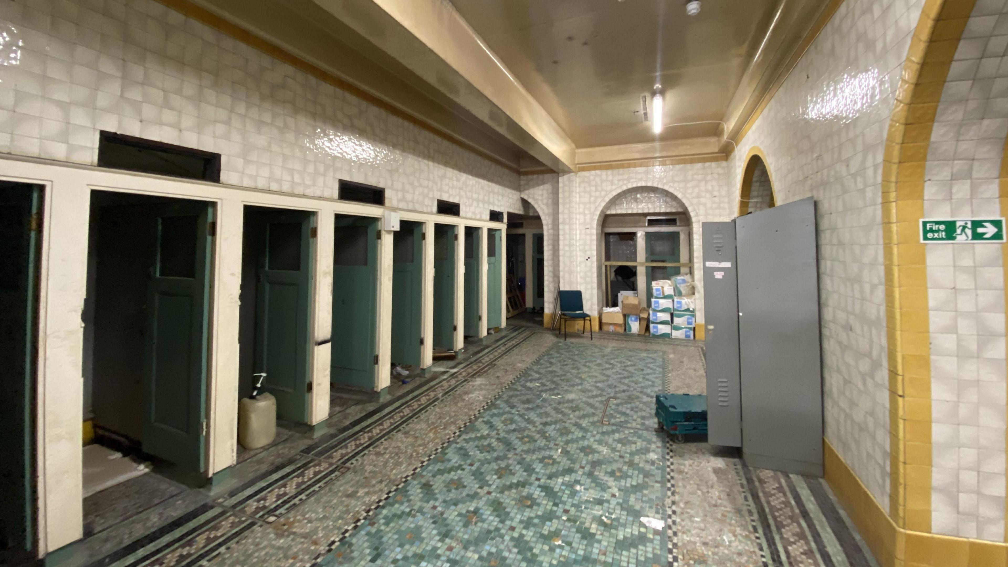 A room covered in white and yellow tiling. The floor is blue mosaic. This room was formerly the women's toilets at Brighton Station