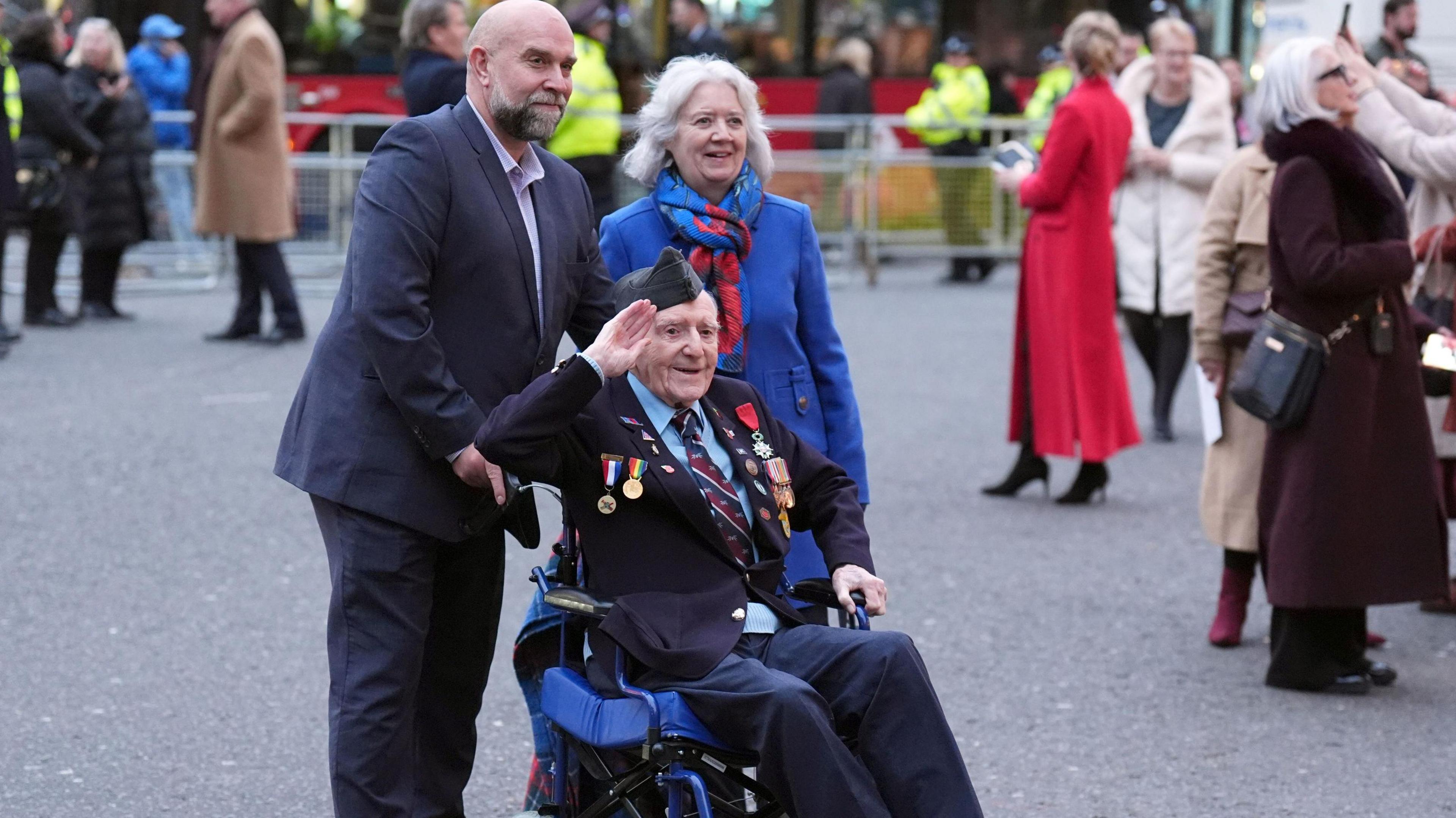 D-Day veteran and Royal British Legion Ambassador Bernard Morgan salutes as he arrives for the annual service. He is accompanied by two others.