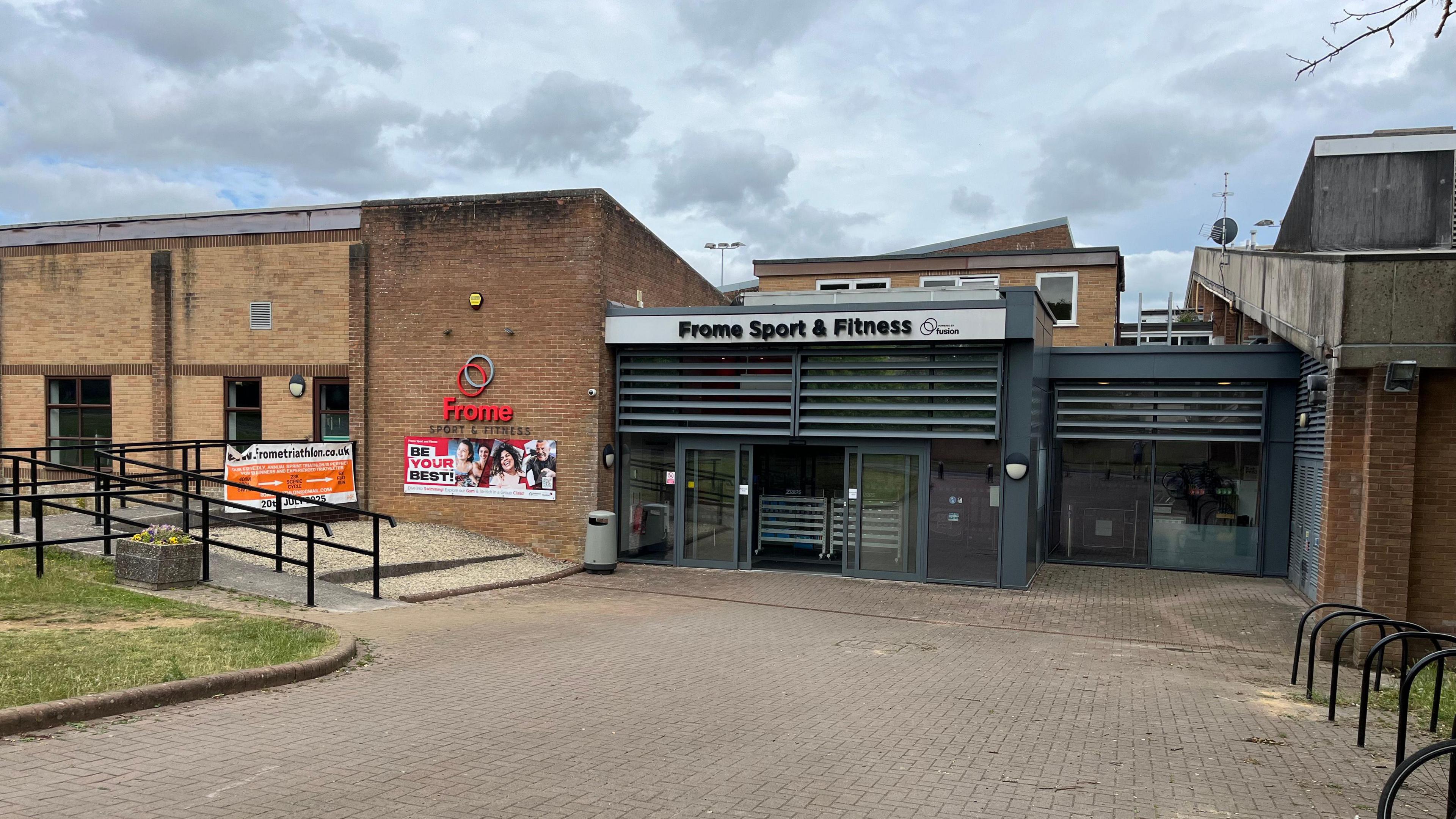 Entrance of Frome Sport & Fitness centre. It's a bricked building with a huge sign above the double doors.