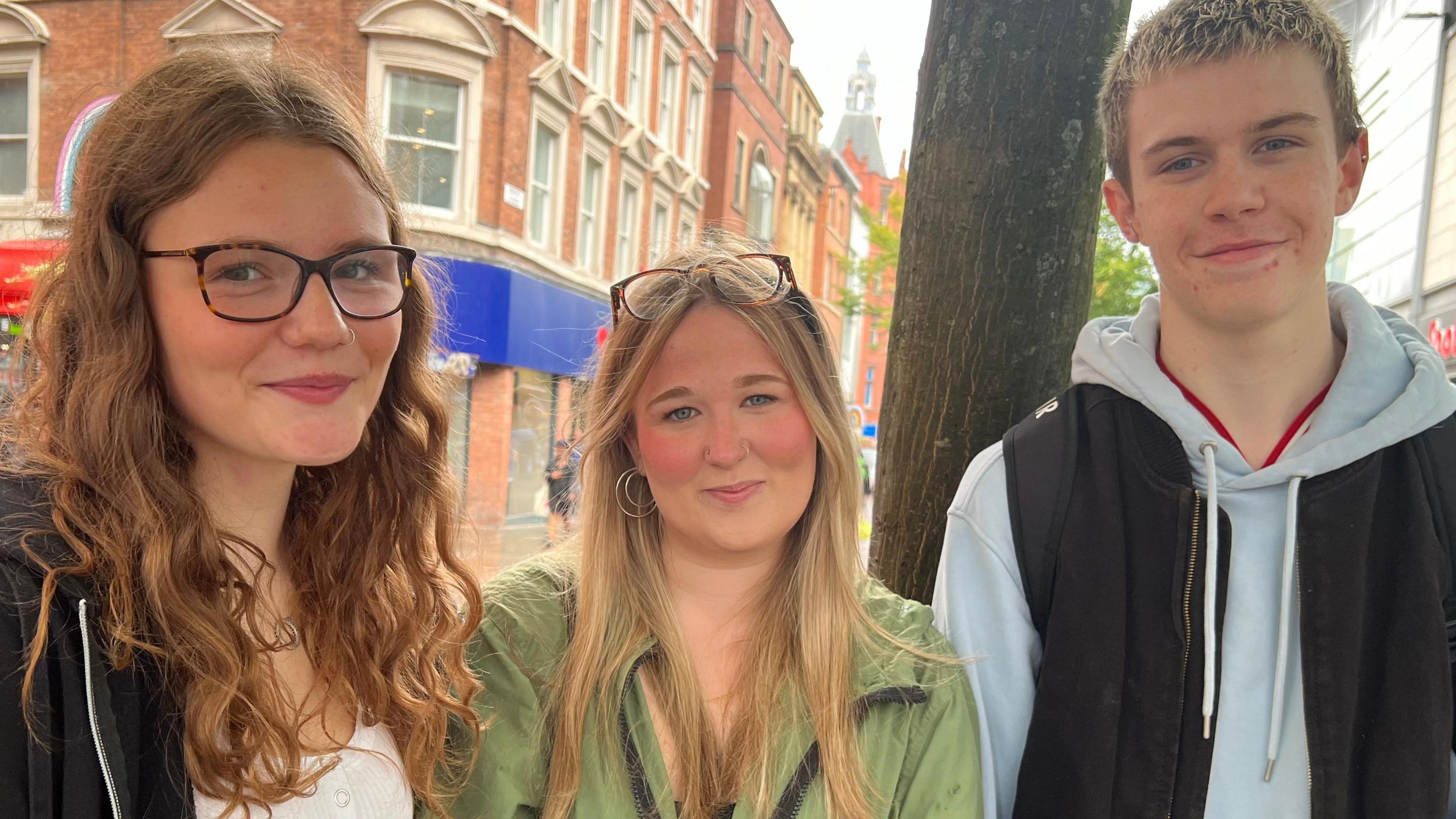 Scarlett Thornton flanked by her friends posing for a photograph in Manchester city centre