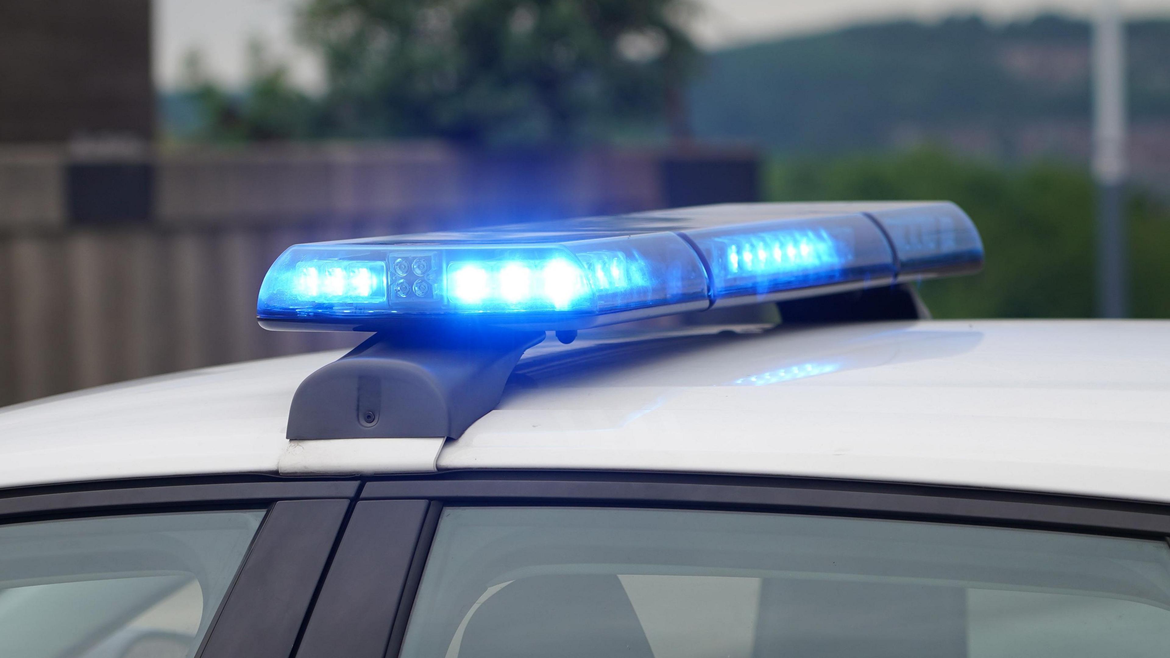 The white roof of a police car showing two blue flashing lights. 