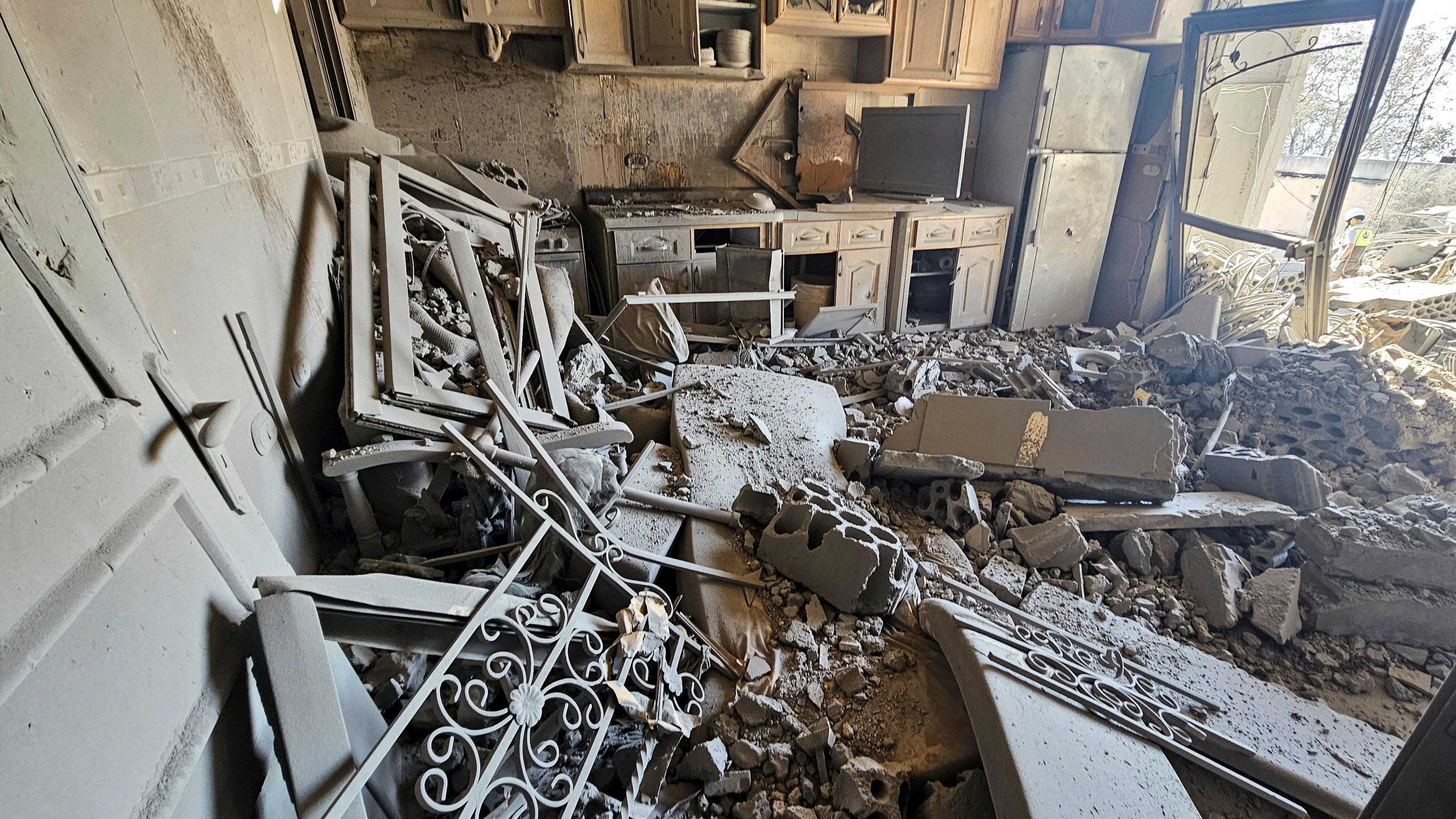 The inside of a damaged house shows a floor covered in rubble and dust after an Israeli strike