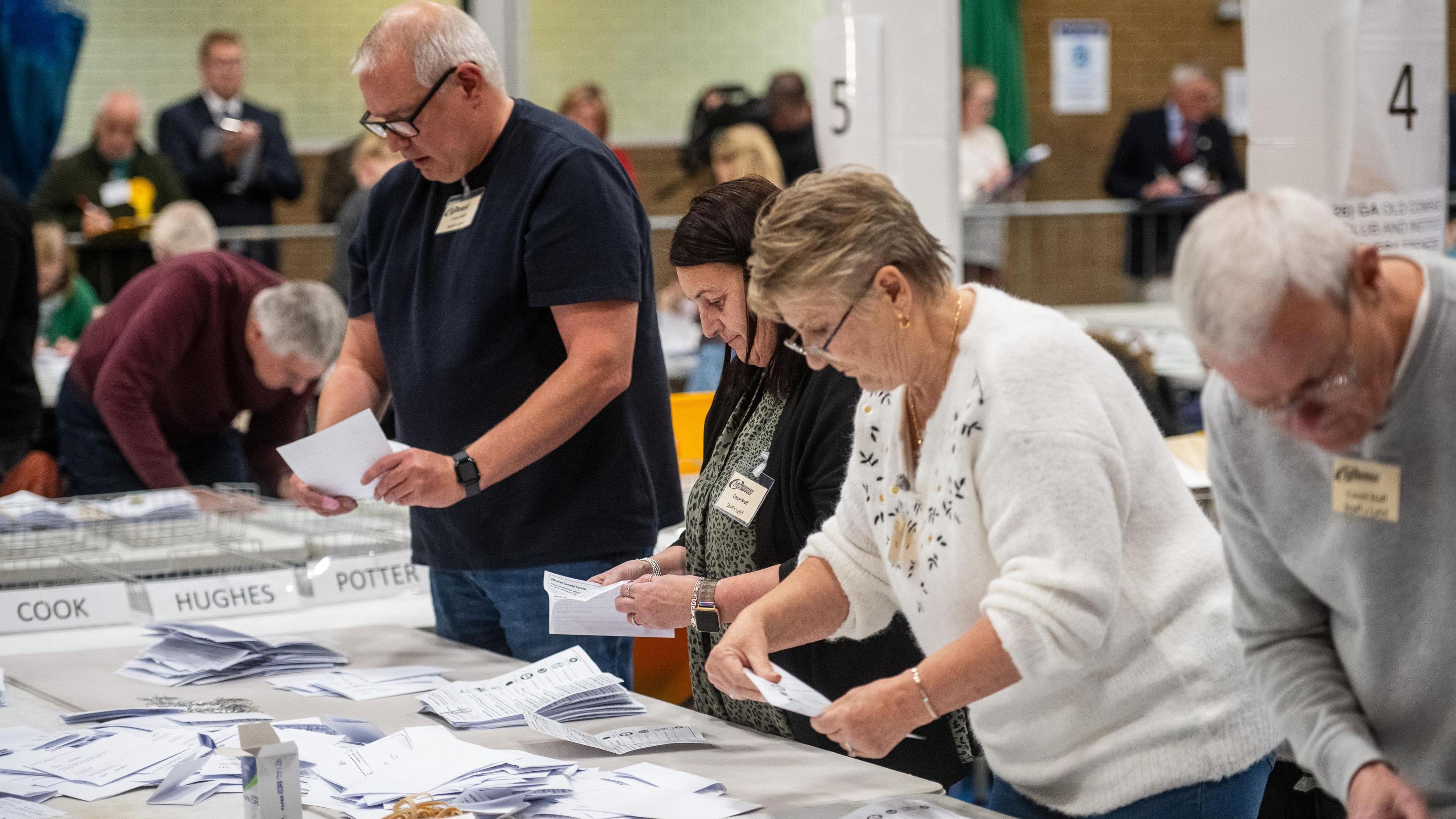 Four people are seen lining up counting votes