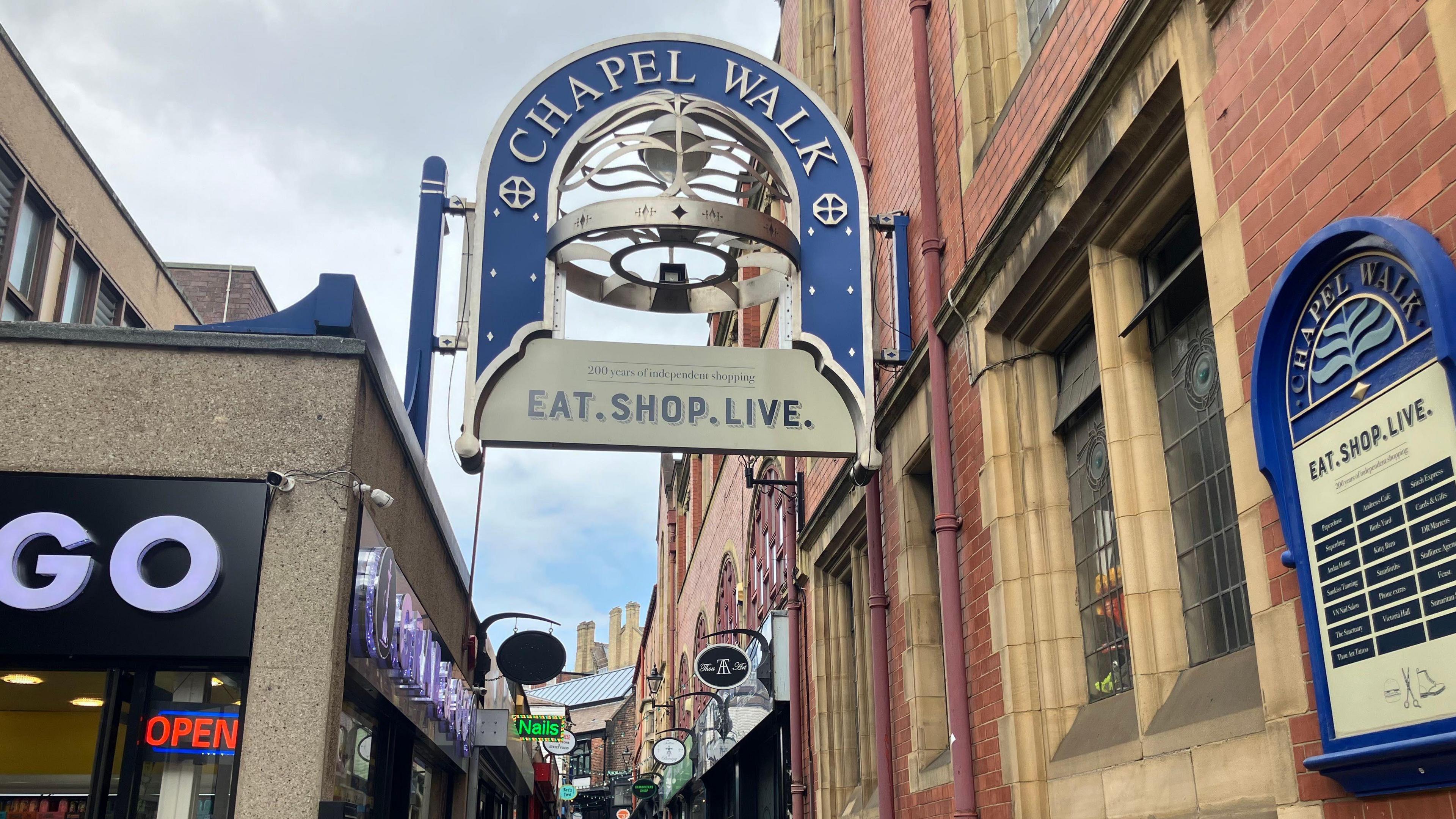 An entrance sign to Chapel Walk at the bottom of a winding alleyway.