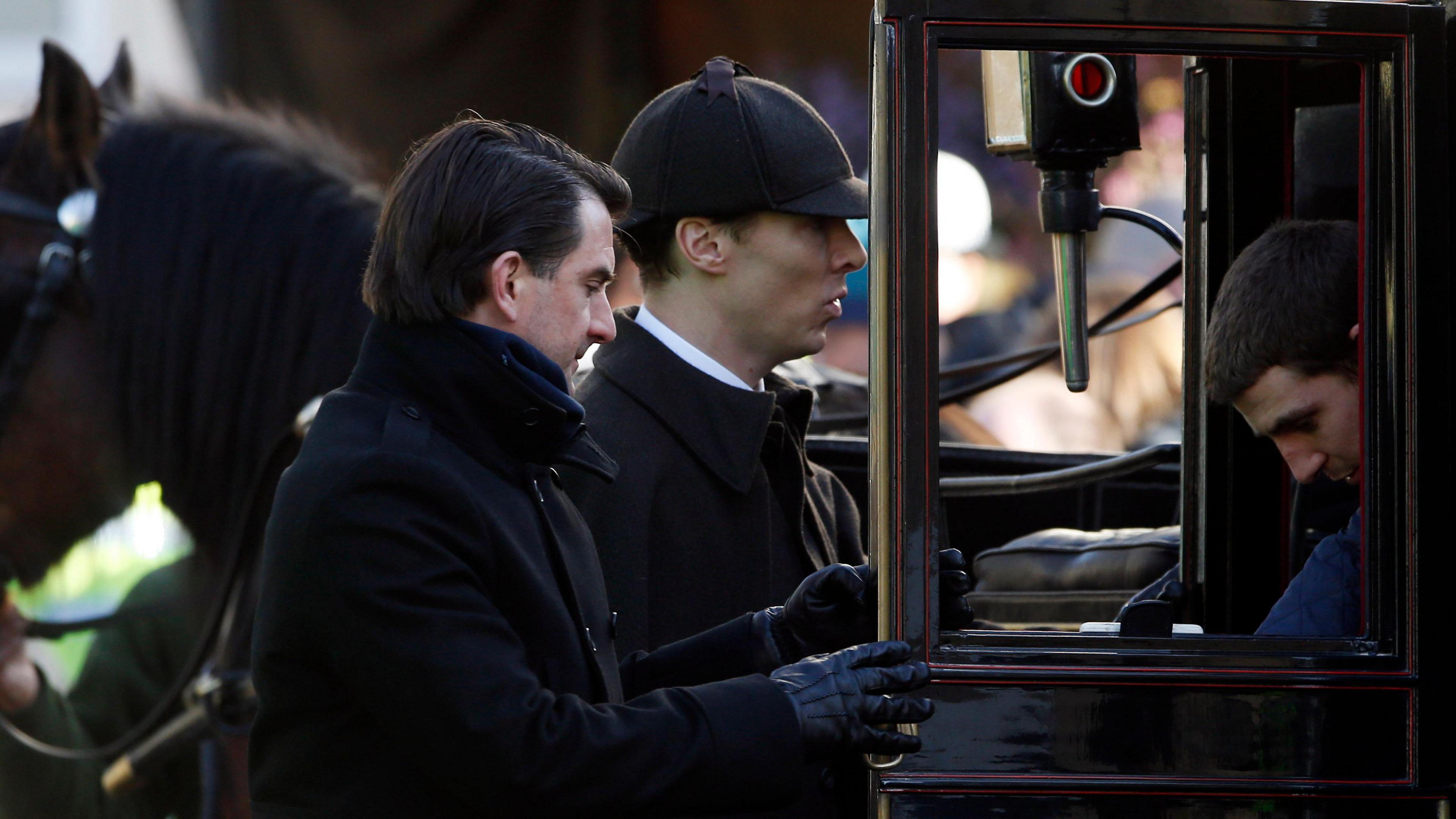 Benedict Cumberbatch wearing black and entering carriage while playing Sherlock Holmes.