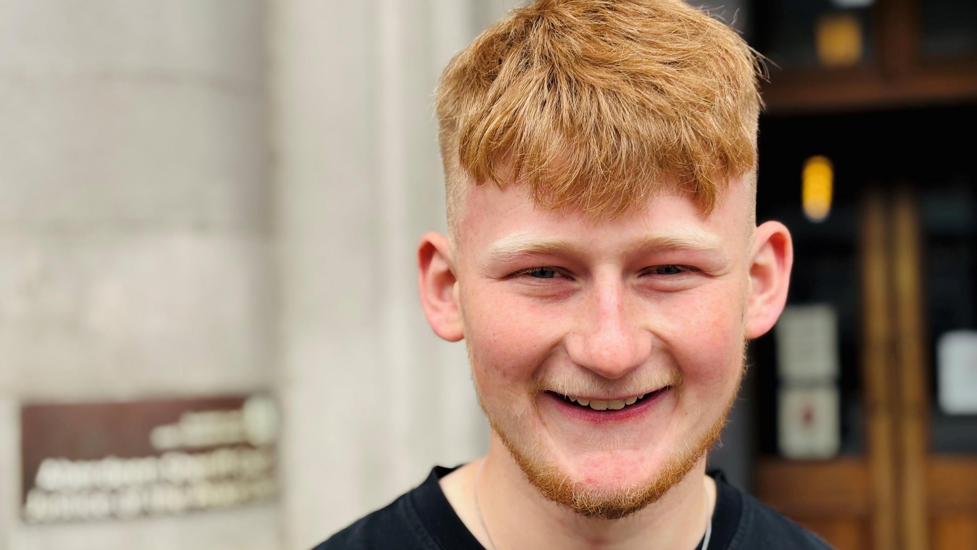 Adam Golebiewski, smiling at camera outside court.