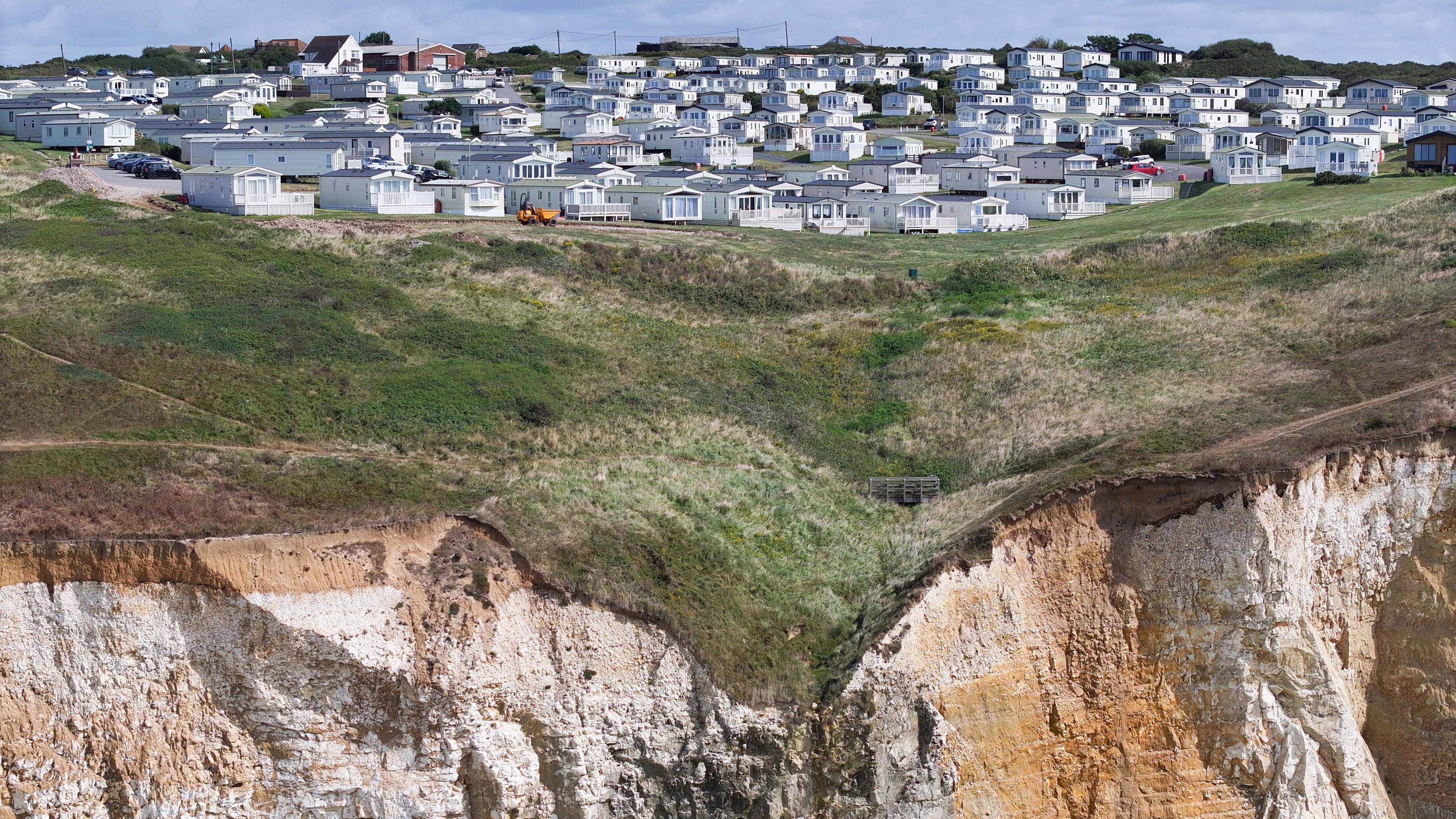 A drone shot of static caravans with the edge of the cliff in the foreground