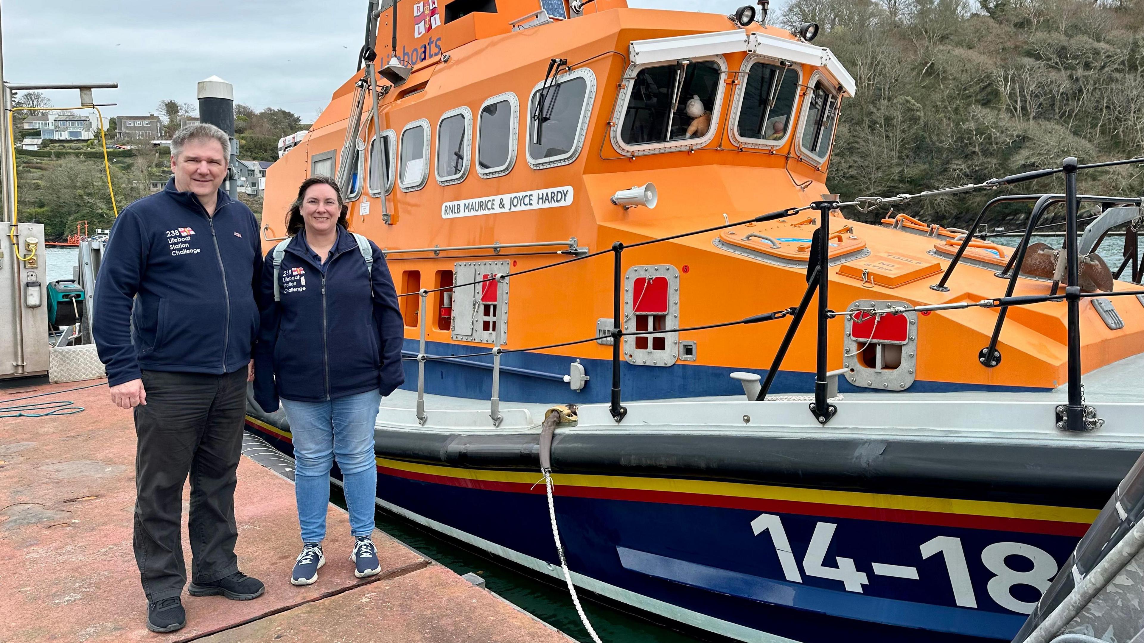 Allan and Helen Thornhill standing on a jetty next to the RNLI lifeboat in Fowey in Cornwall
