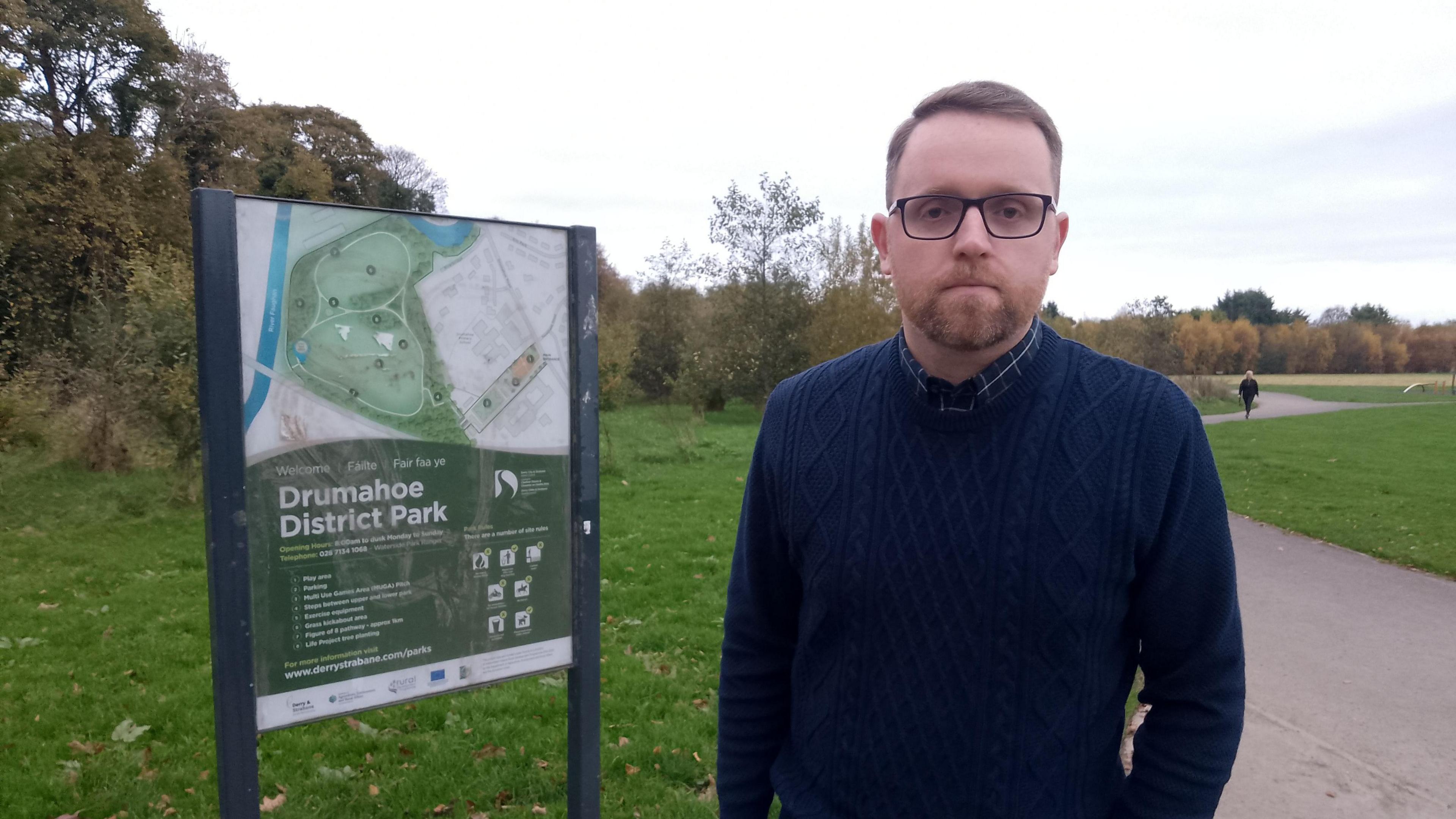 Gary Middleton wearing a navy sweatshirt and a navy shirt pictured in front of a Drumahoe District Park sign.