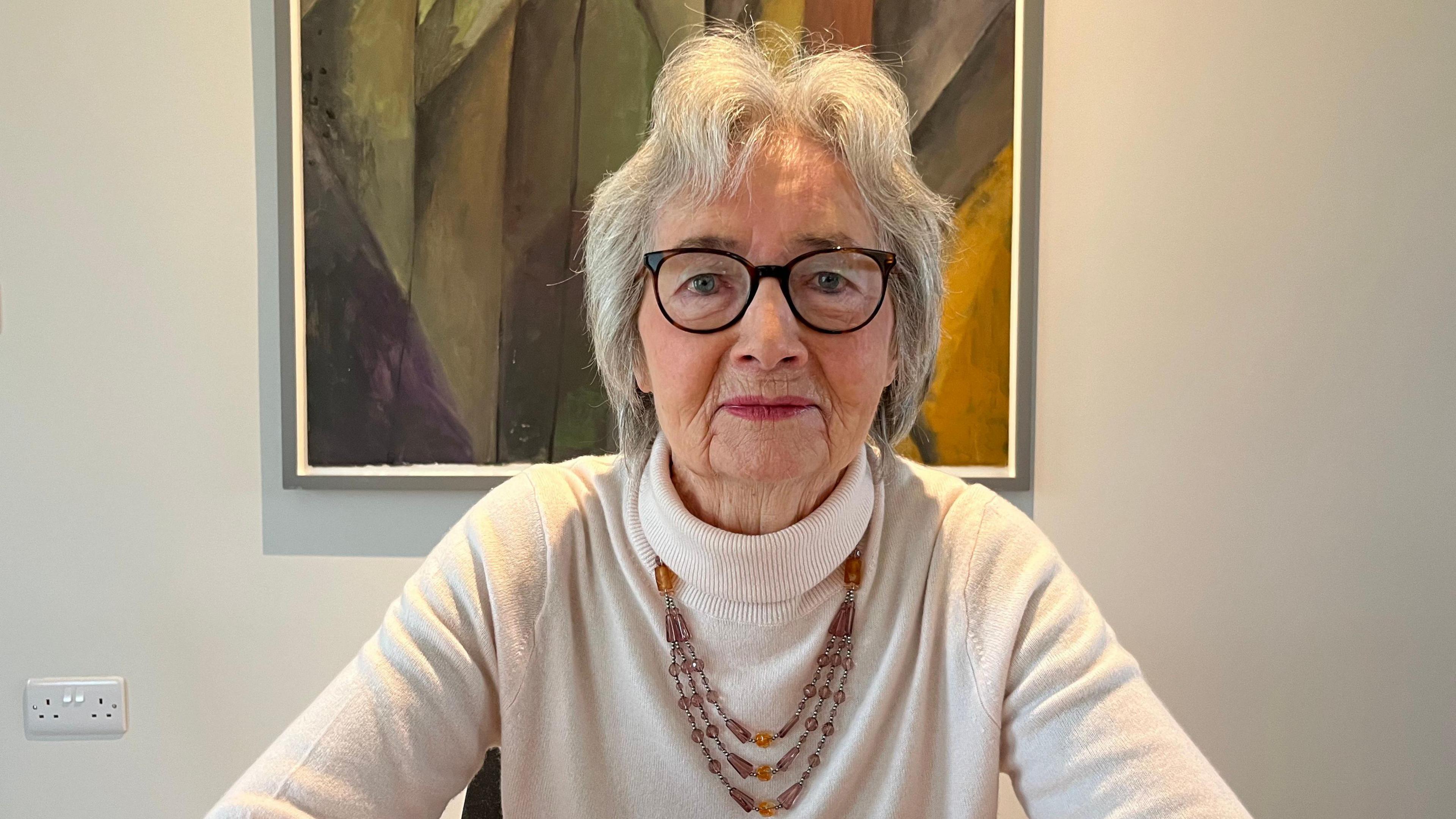 Former SDLP minister Bríd Rodgers looking directly at the camera. She has wavy grey hair and black rimmed glasses.   She is wearing a cream-coloured turtle-neck jumper and a brown beaded necklace. 