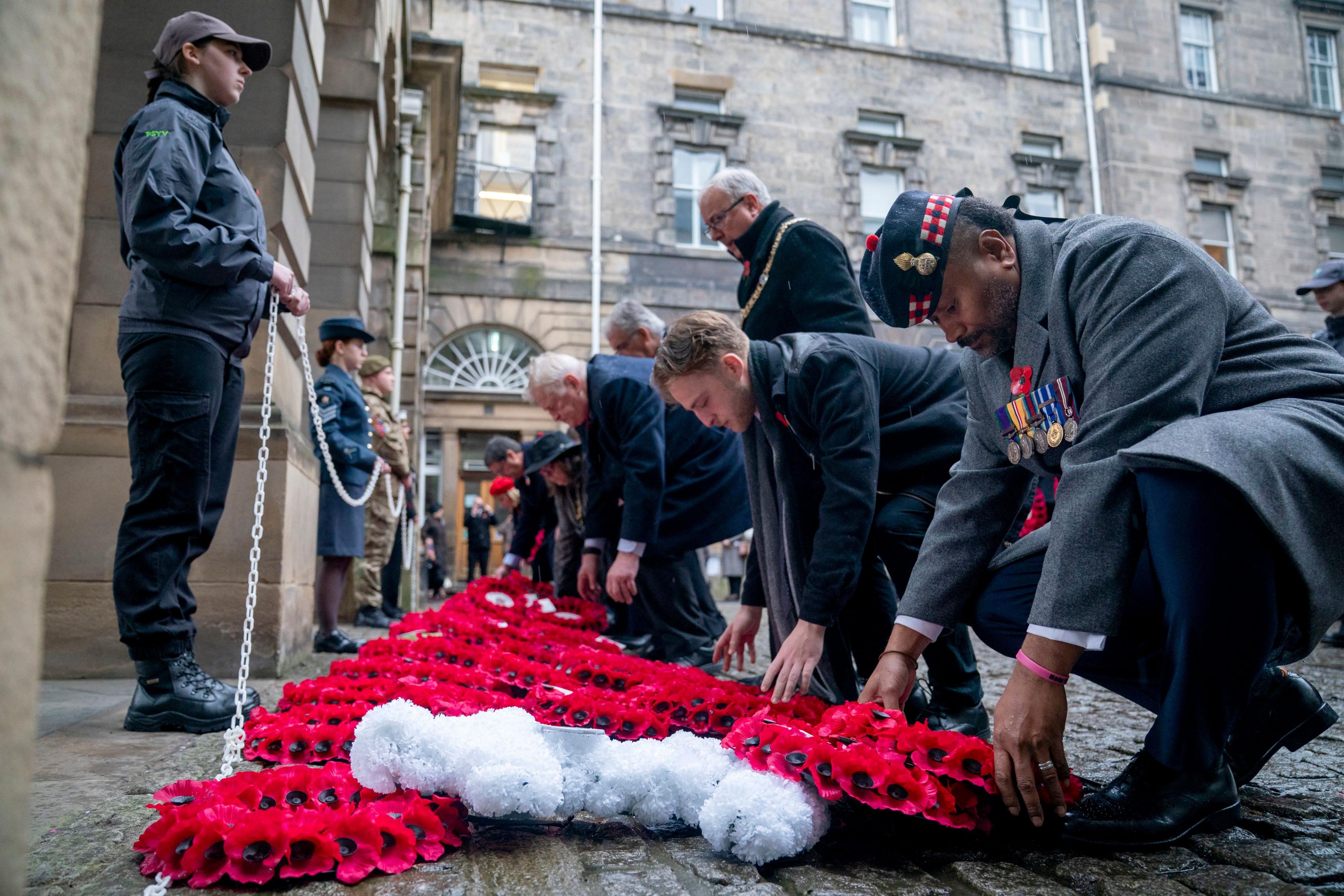 People lay red poppy wreaths during a Remembrance Sunday ceremony at the Stone of Remembrance outside the City Chambers in Edinburgh.