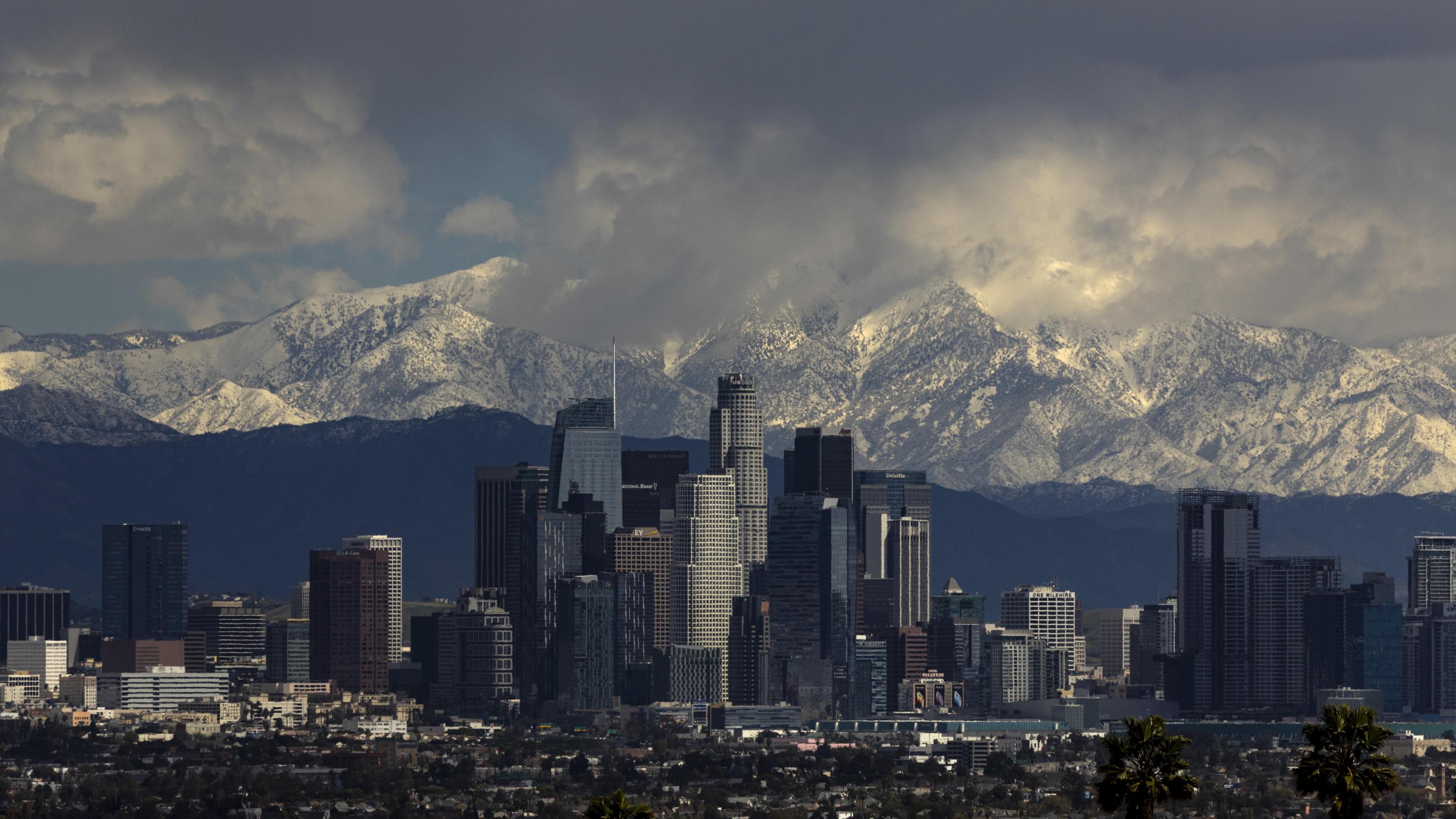 The San Bernardino Mountains covered in snow above downtown Los Angeles under a menacing sky