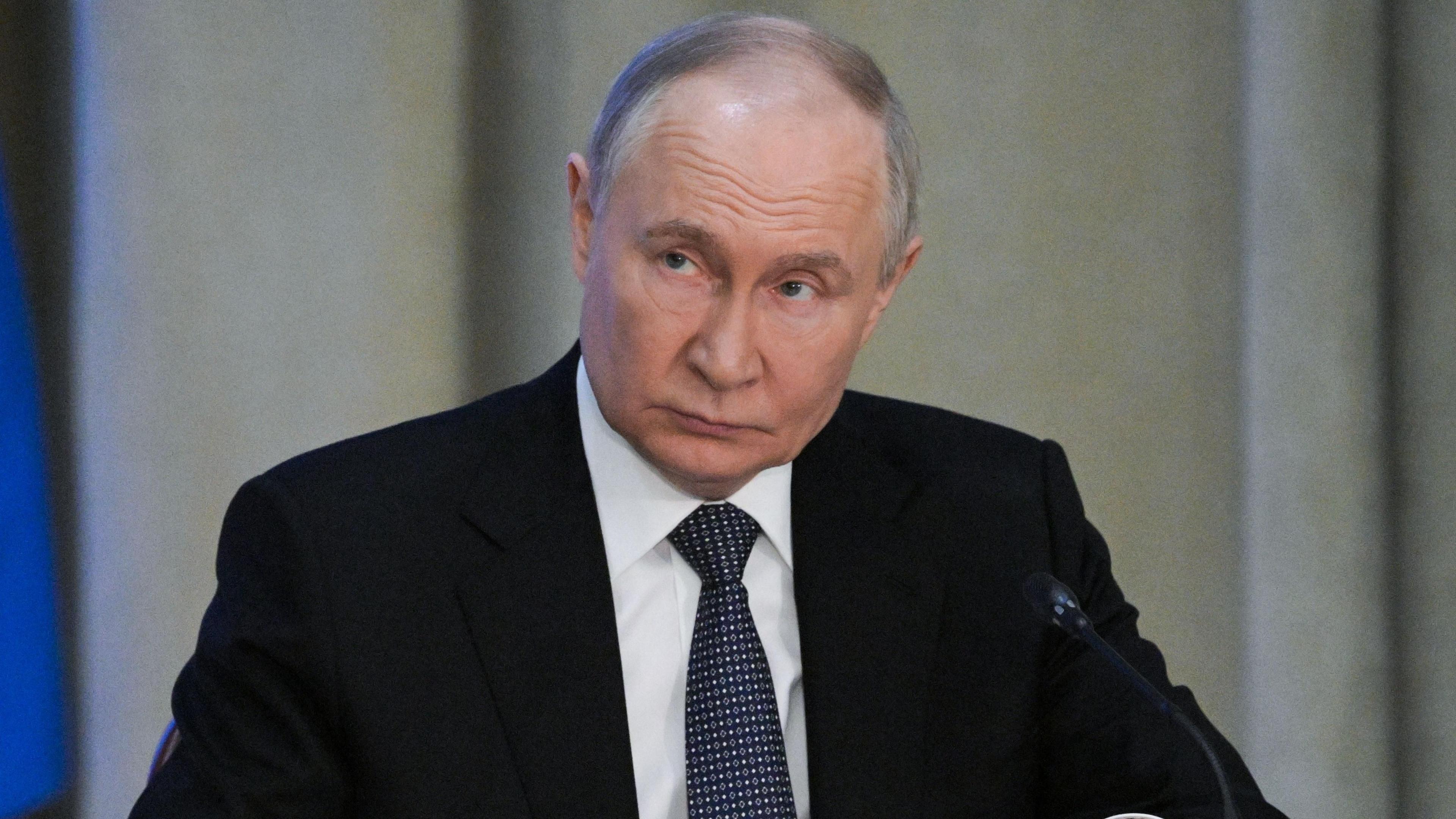 Vladimir Putin at meeting of the Russian prosecutor general's office. He is wearing a suit and tie, and is looking up and to the right.