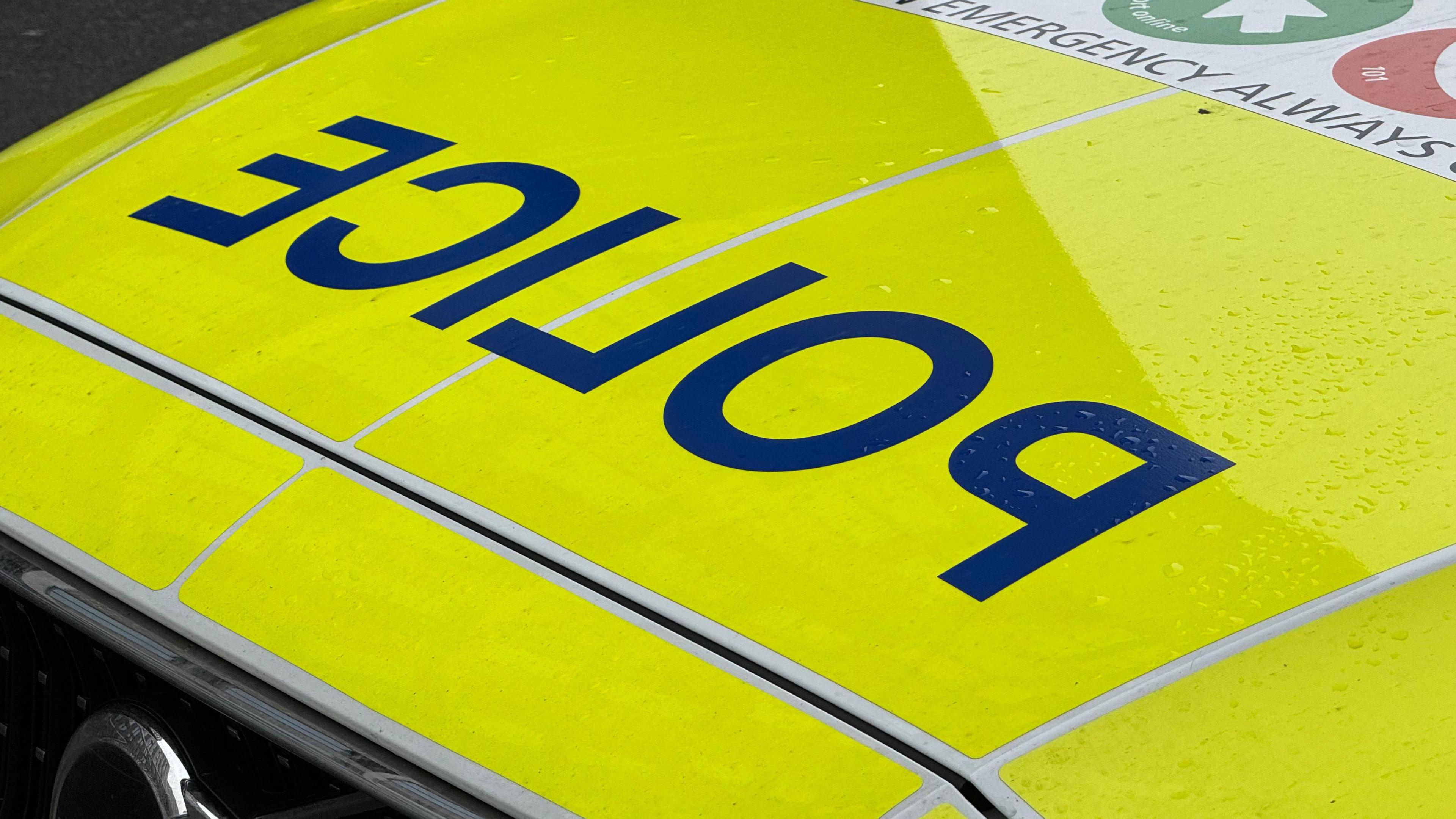 The bonnet of a police car, with the word police spelt in reverse lettering.