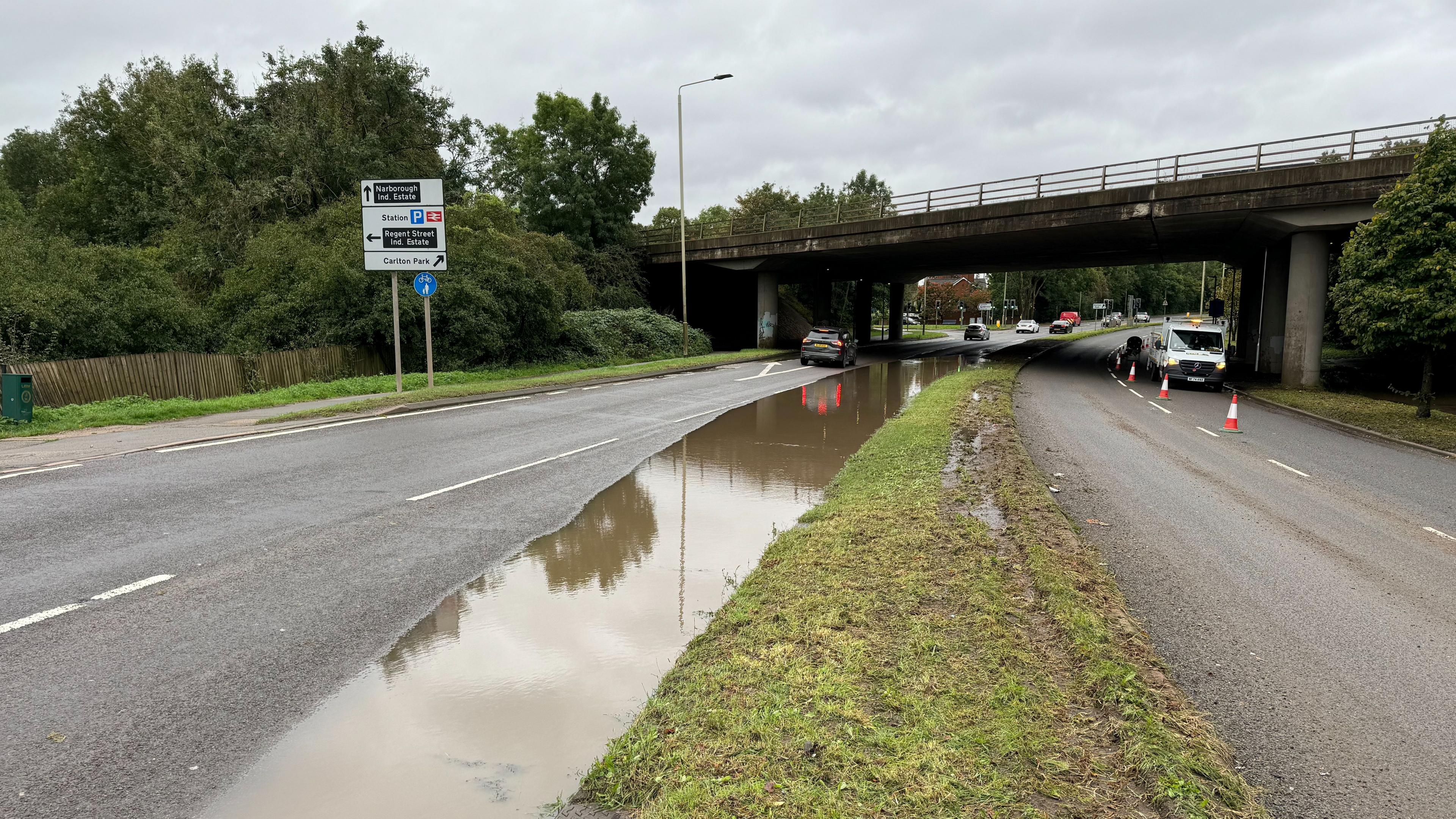 The outside lane of a dual carriageway is left partially covered by water on the approach to a bridge. 