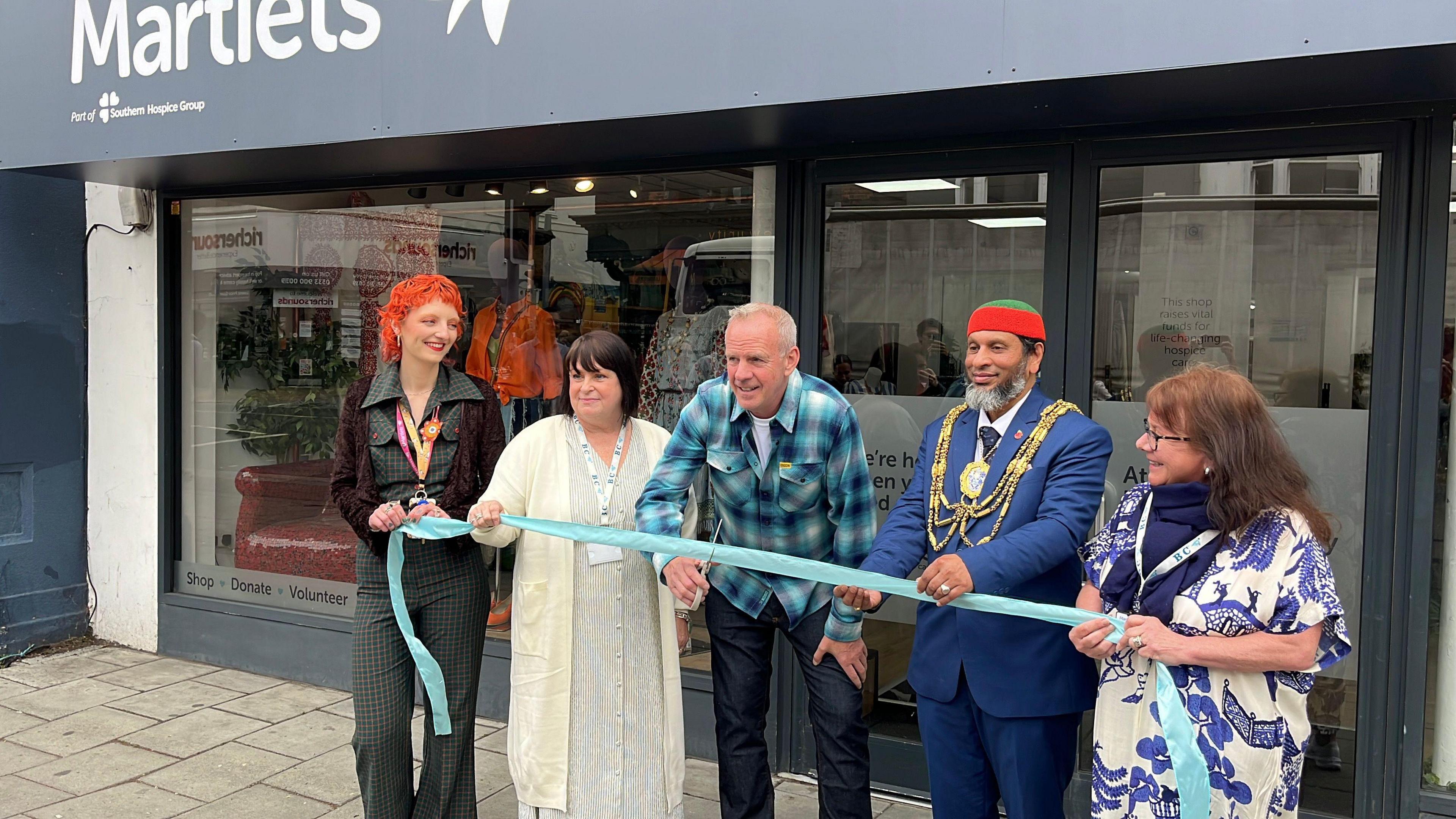 Norman Cook (centre) cuts the ribbon outside the refurbished Martlets hospice shop in London Road in Brighton