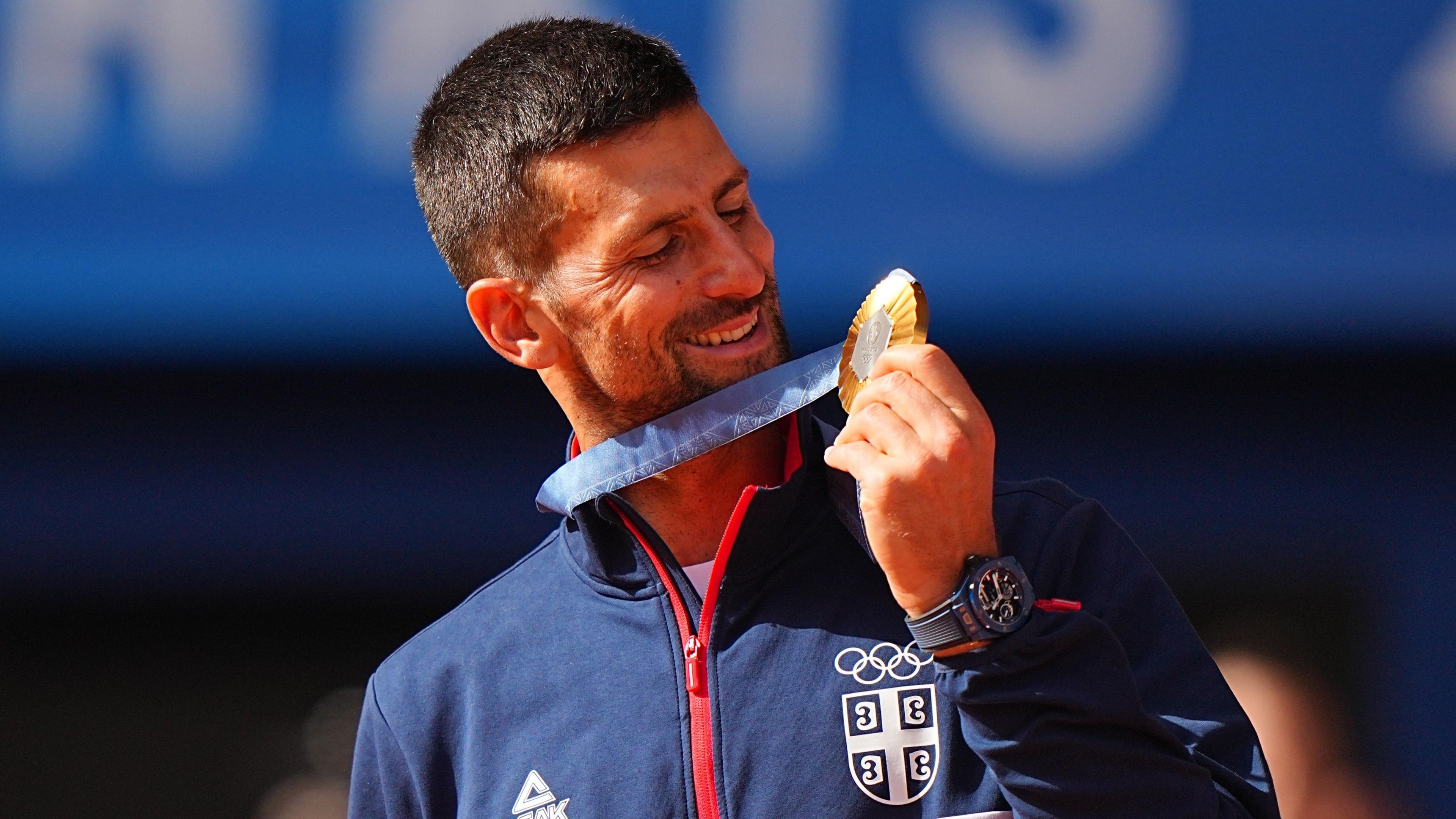 Novak Djokovic smiles at his Olympic gold medal after triumphing at the 2024 Games