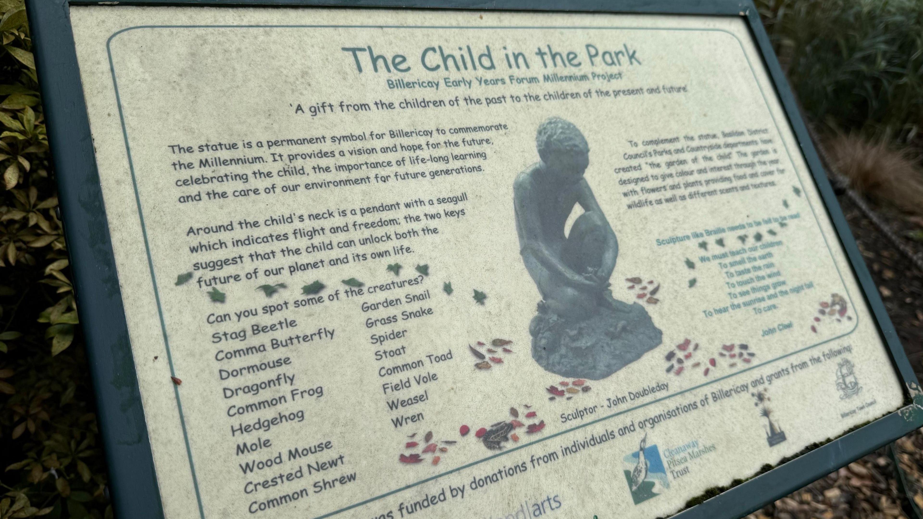 A sign in a park with the heading "The Child in the Park - Billericay Early Years Forum Millennium Project". It says: "The statue is a permanent symbol for Billericay to commemorate the Millennium. It provides a vision and hope for the future, celebrating the child, the importance of life-long learning, and the care of our environment for future generations."