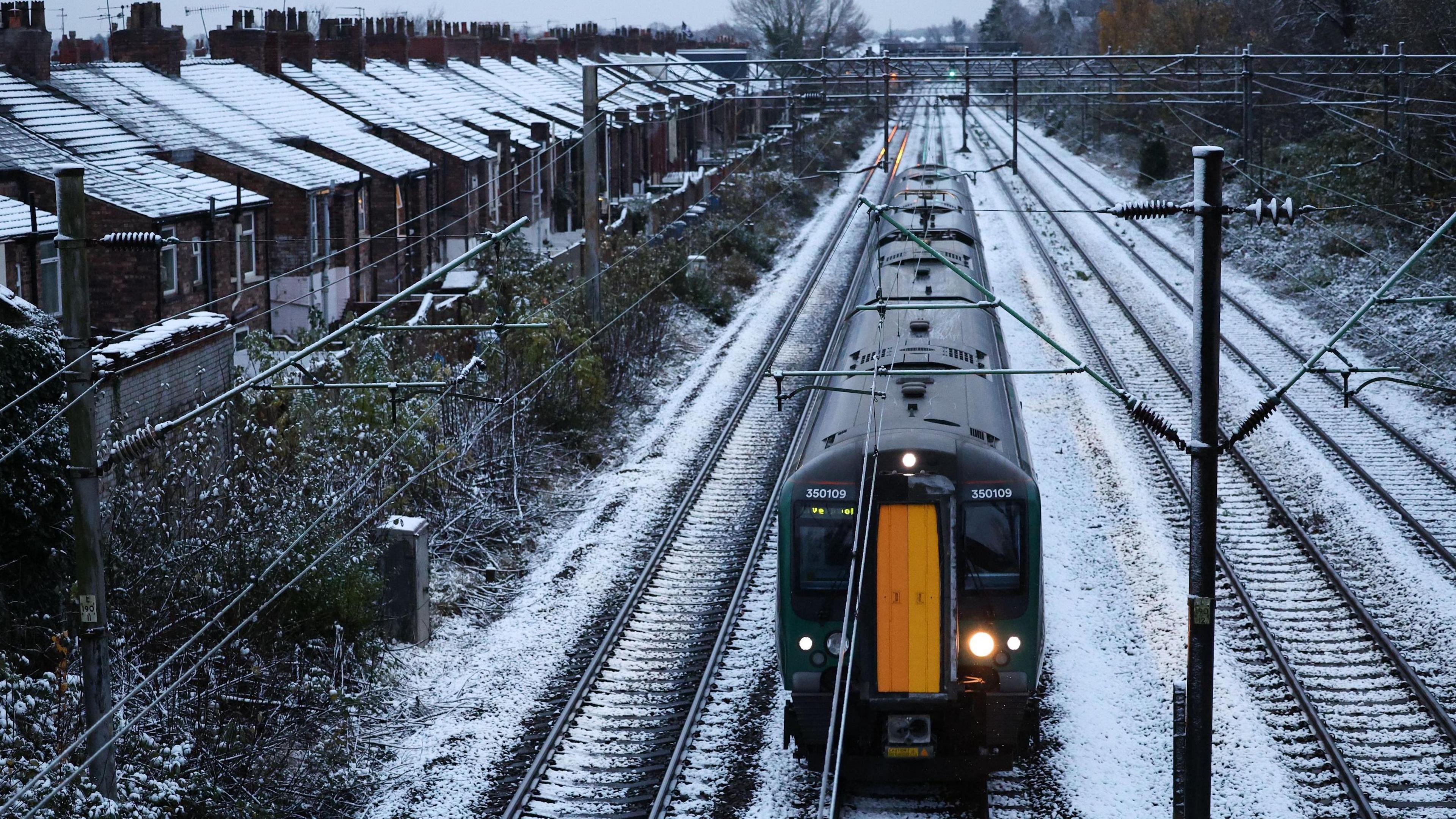 train on snowy tracks near row of houses