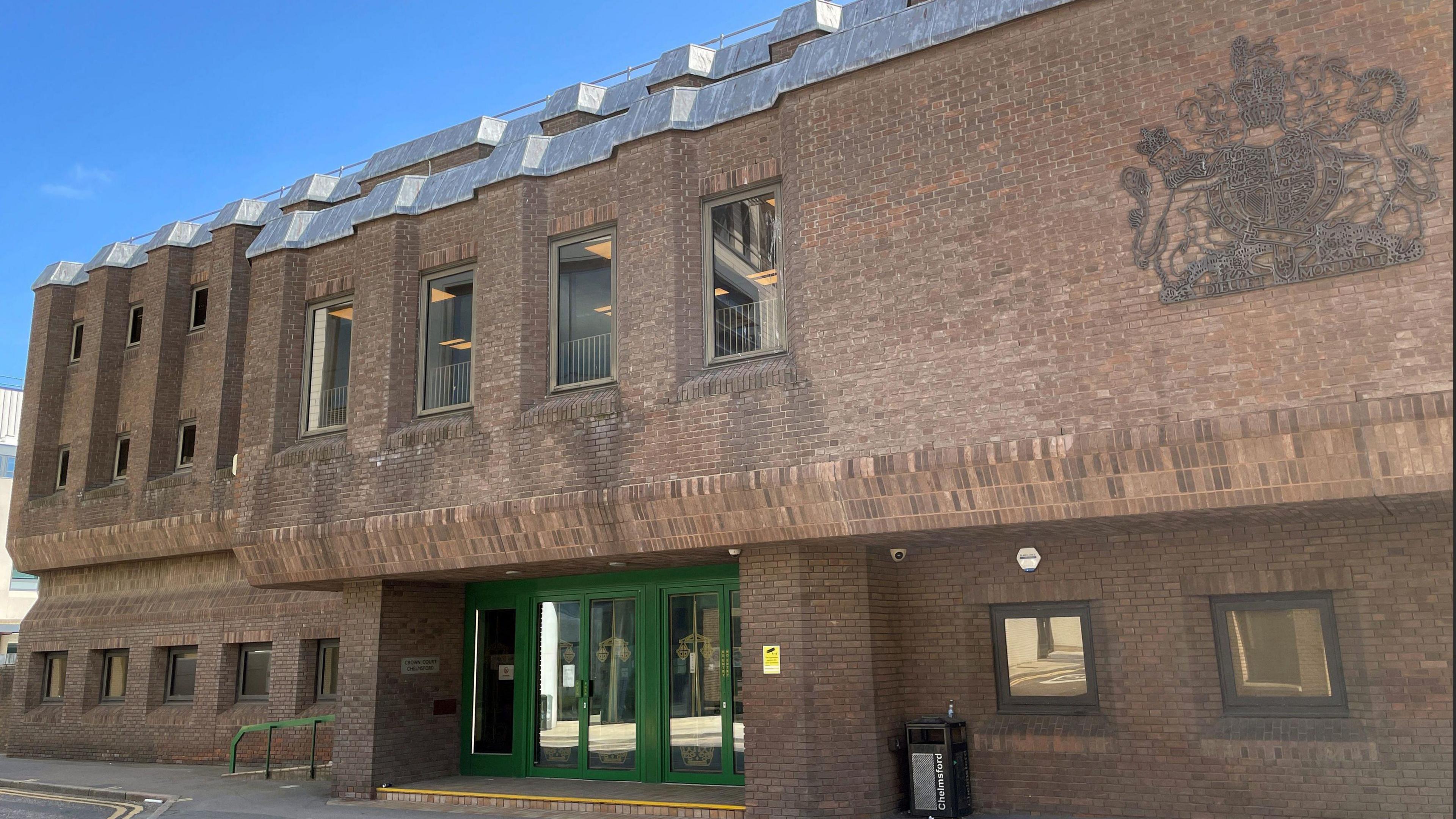 Outside Chelmsford Crown Court, which is a brown, three-storey brick building with green doors.