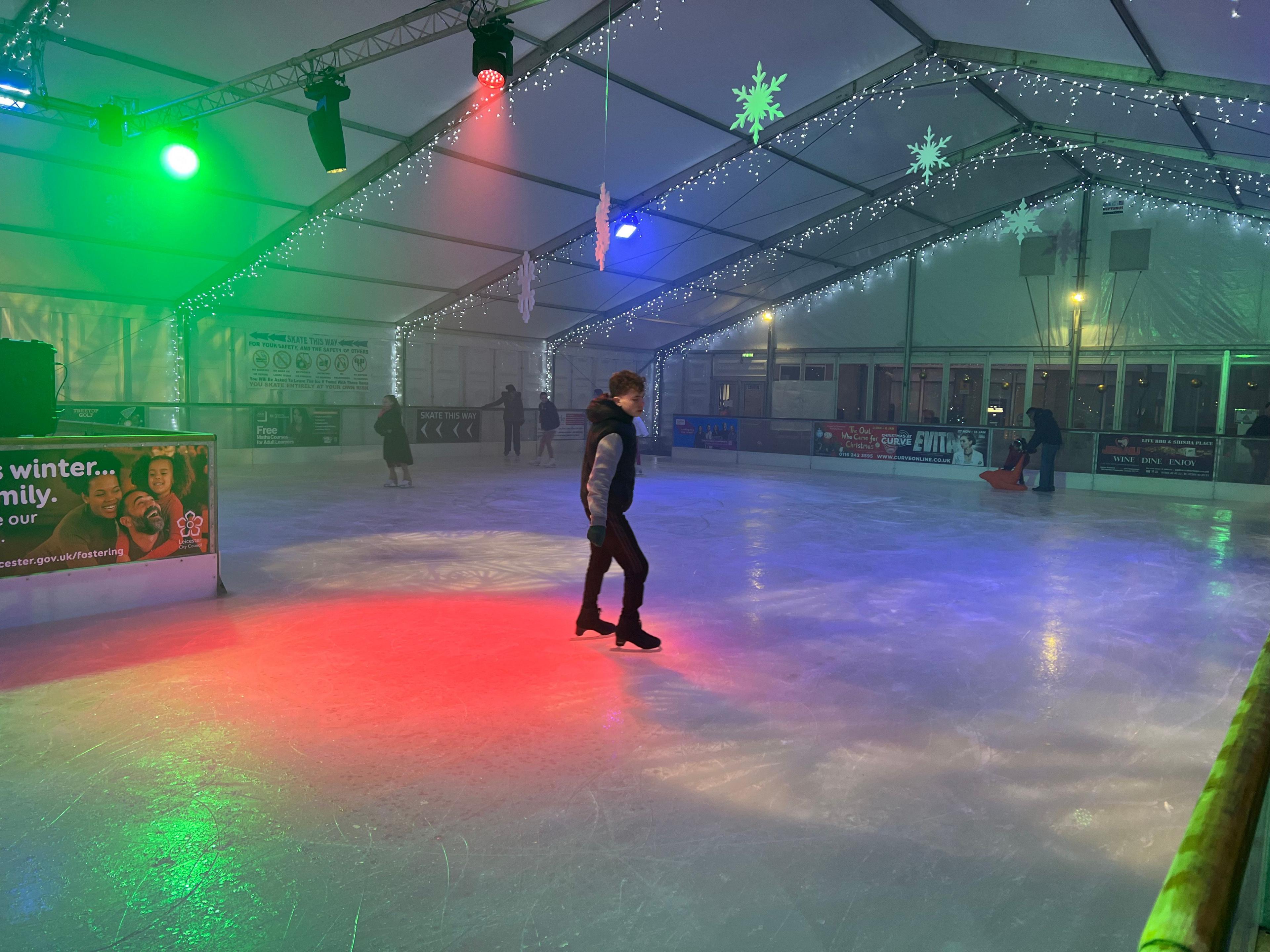 A man skating on an indoor ice rink with disco lights