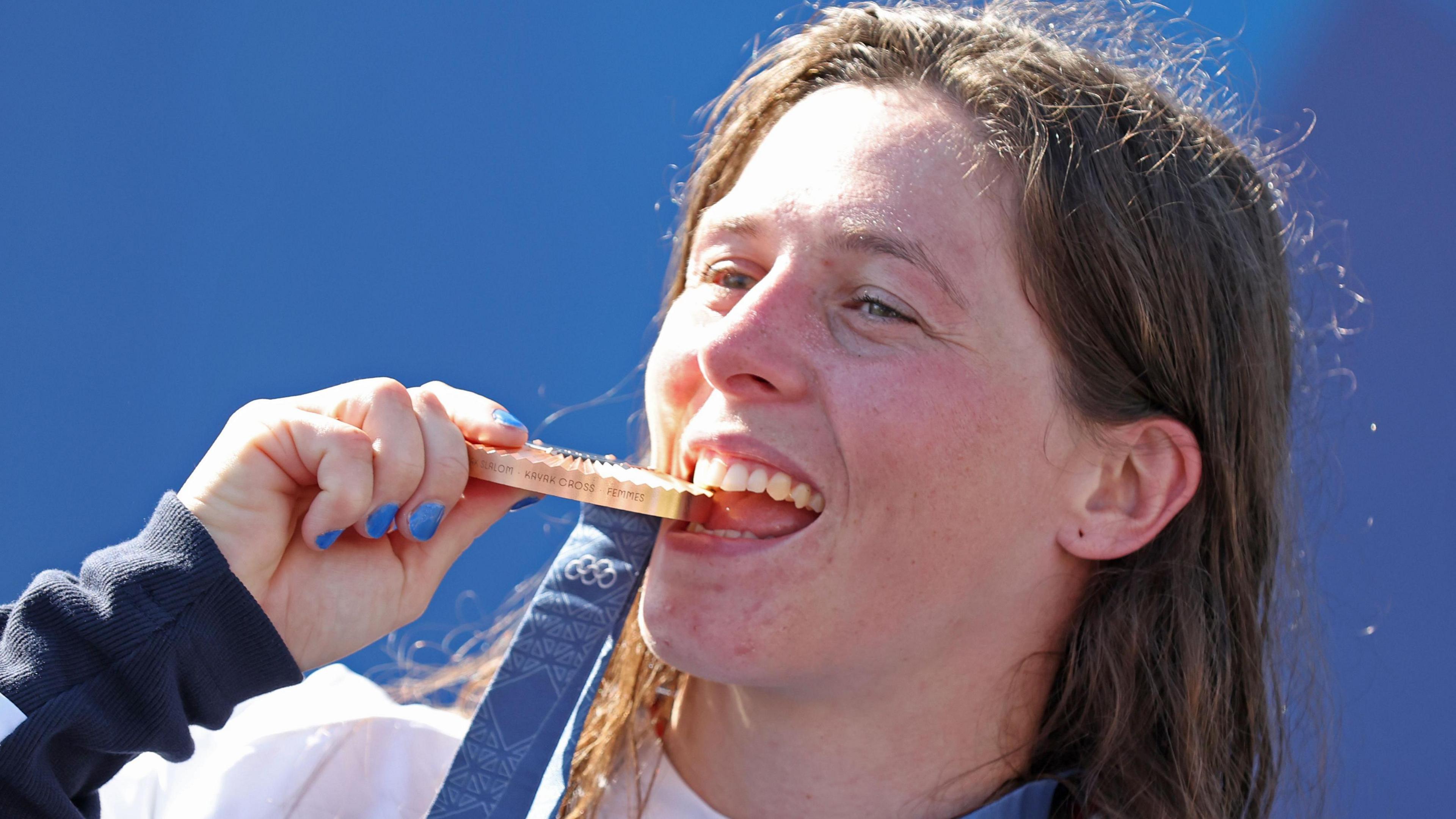 Kimberley Woods biting her bronze medal