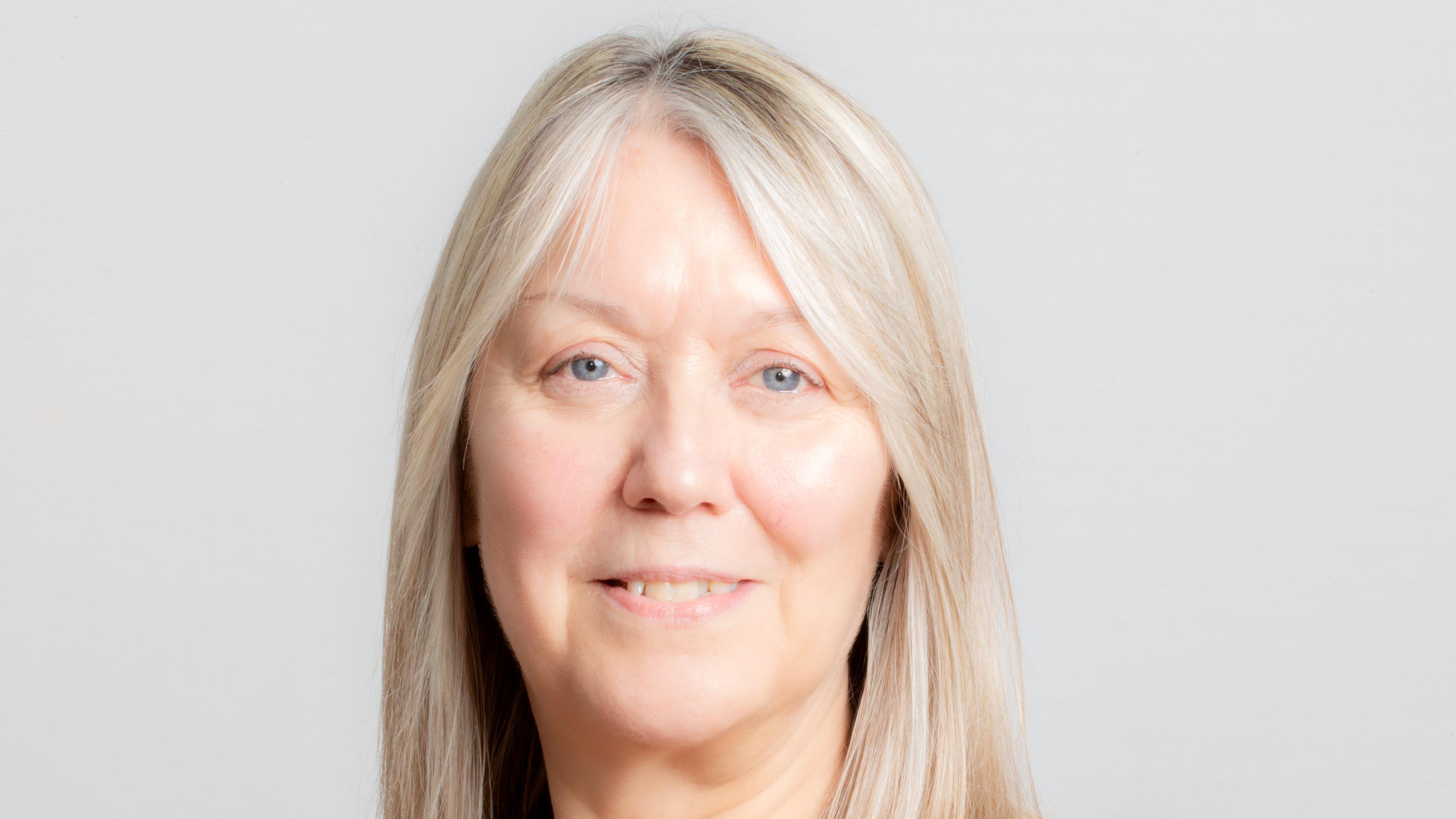 Portrait of Alison smiling straight to camera with blond hair and blue eyes. 