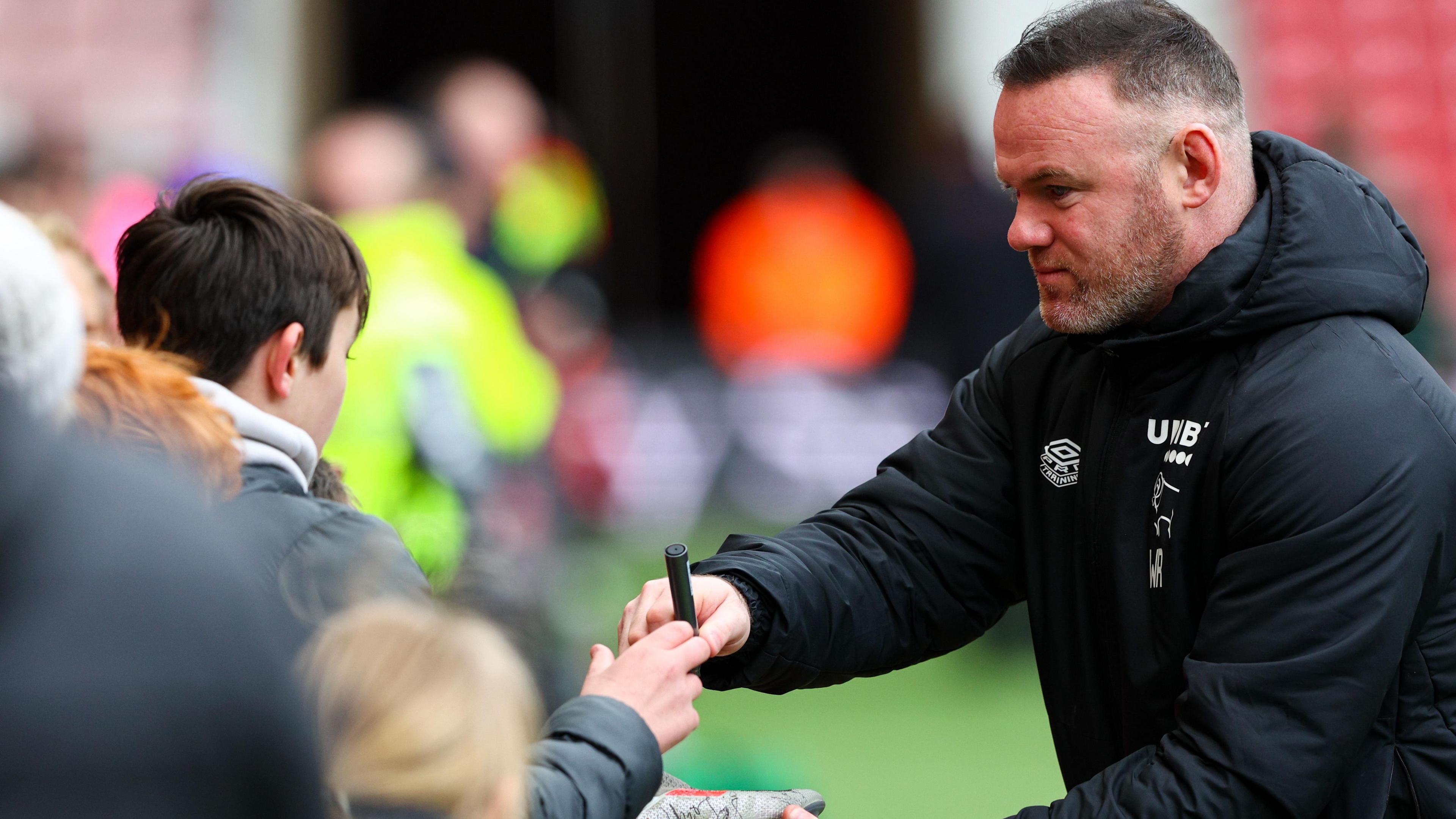 Wayne Rooney signs an autograph at Derby.