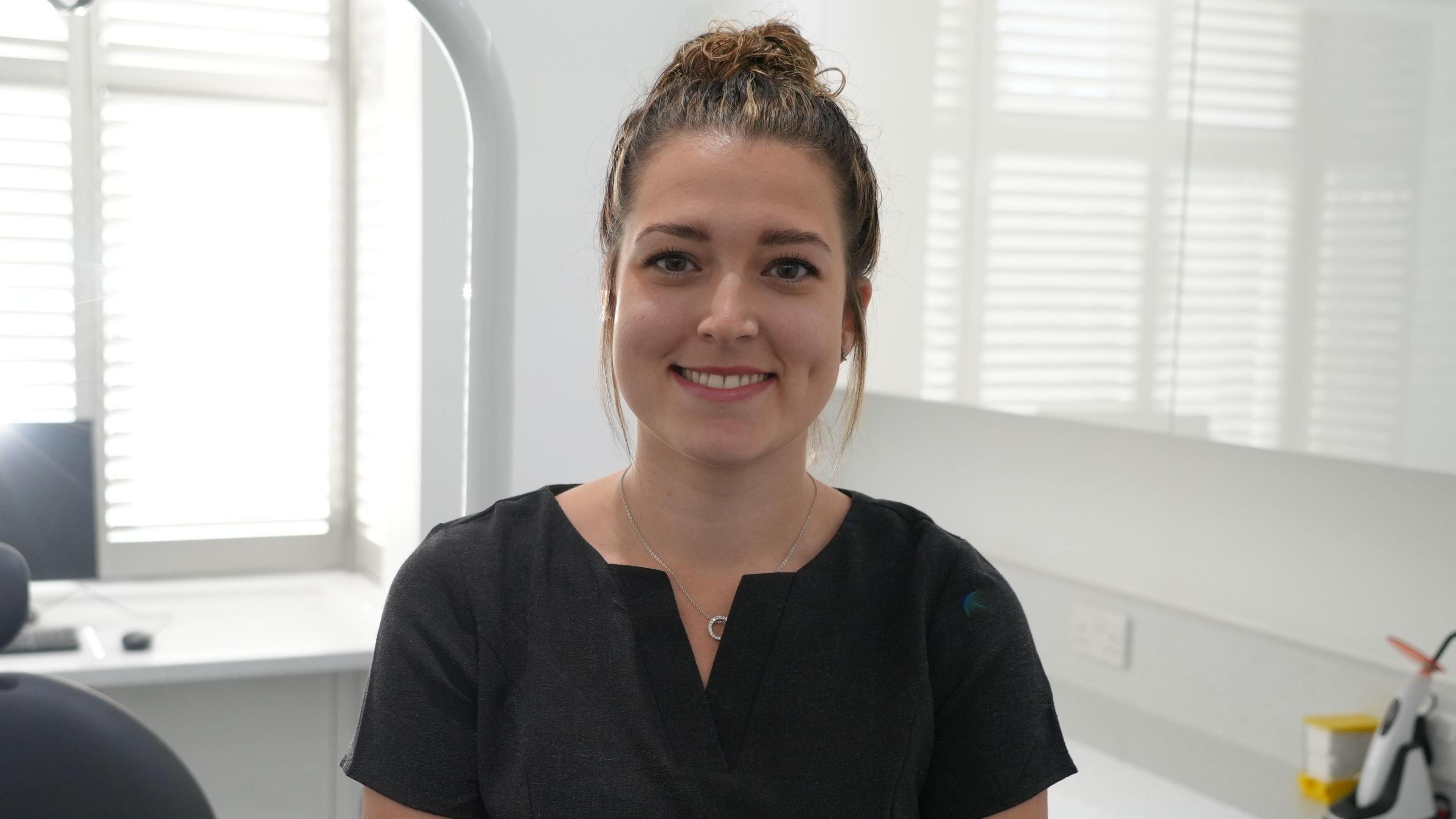 Georgina Rowe, the practice manager at Friends Dental Practice in Norwich. She is looking at the camera and is smiling. Her hair is tied up and she is wearing a black outfit.