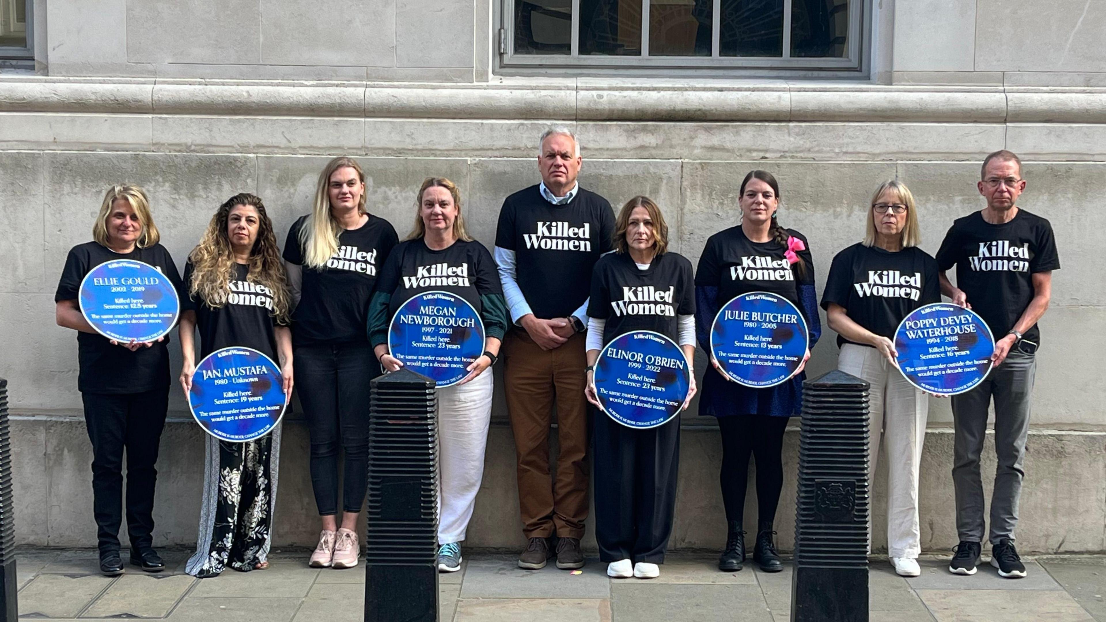 Elaine and Anthony Newborough holding a black and blue plaque with six other families all wearing black t-shirts saying Killed Women