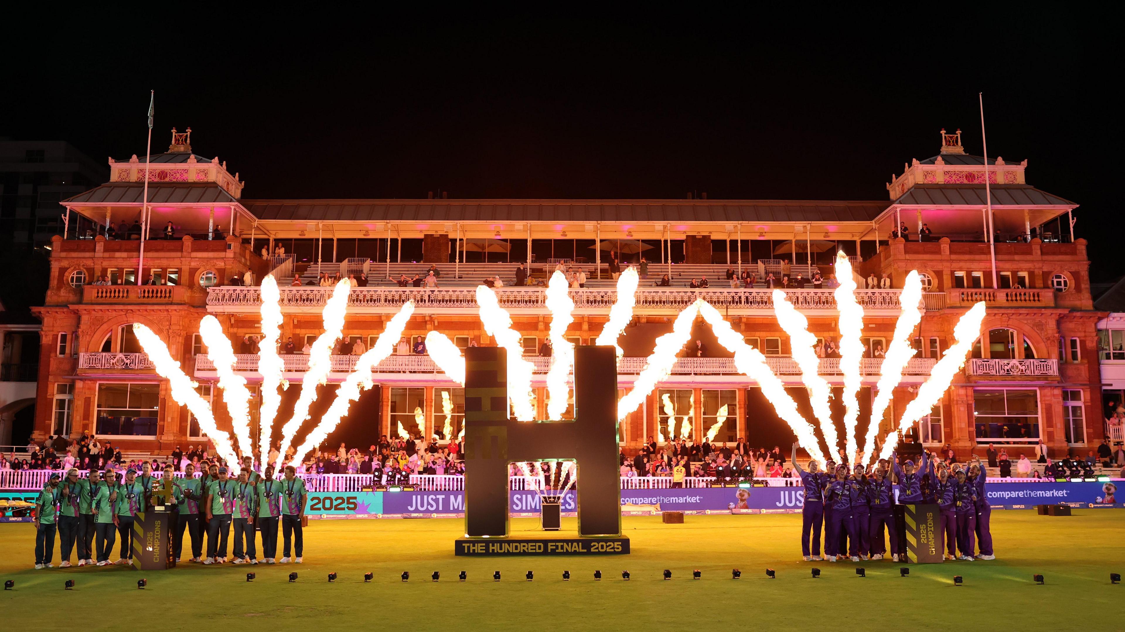 The winners of the Hundred final 2025 lift their trophies. The men's winners (Oval Invincibles) on the left, and the Northern Supercharger's women on the right.
There is a huge 'H' inbetween them, and the backdrop is fireworks in front of the Lord's pavillion at night